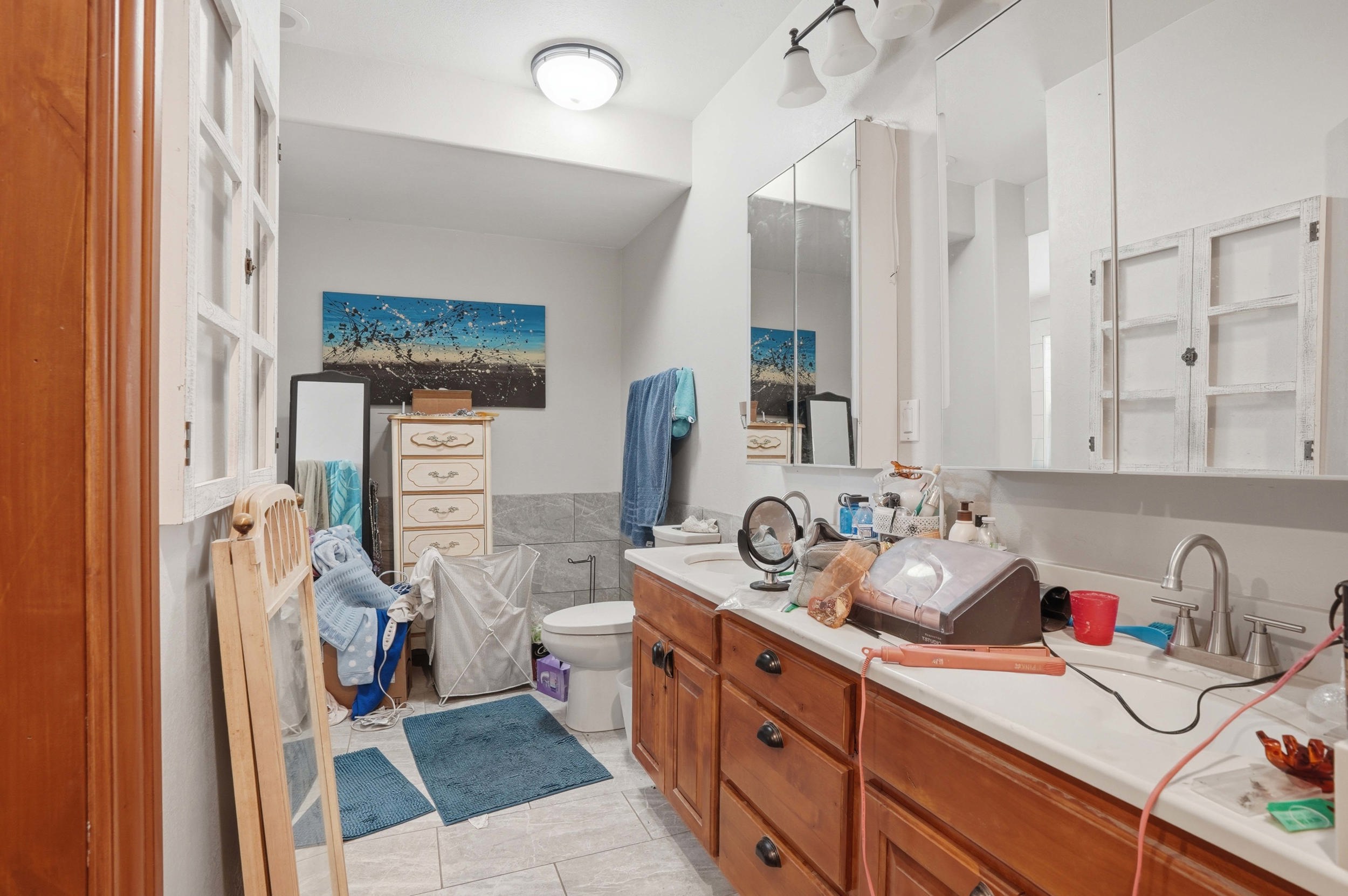 Bathroom featuring a dual vanity with wood cabinetry, white countertops, and a tiled backsplash