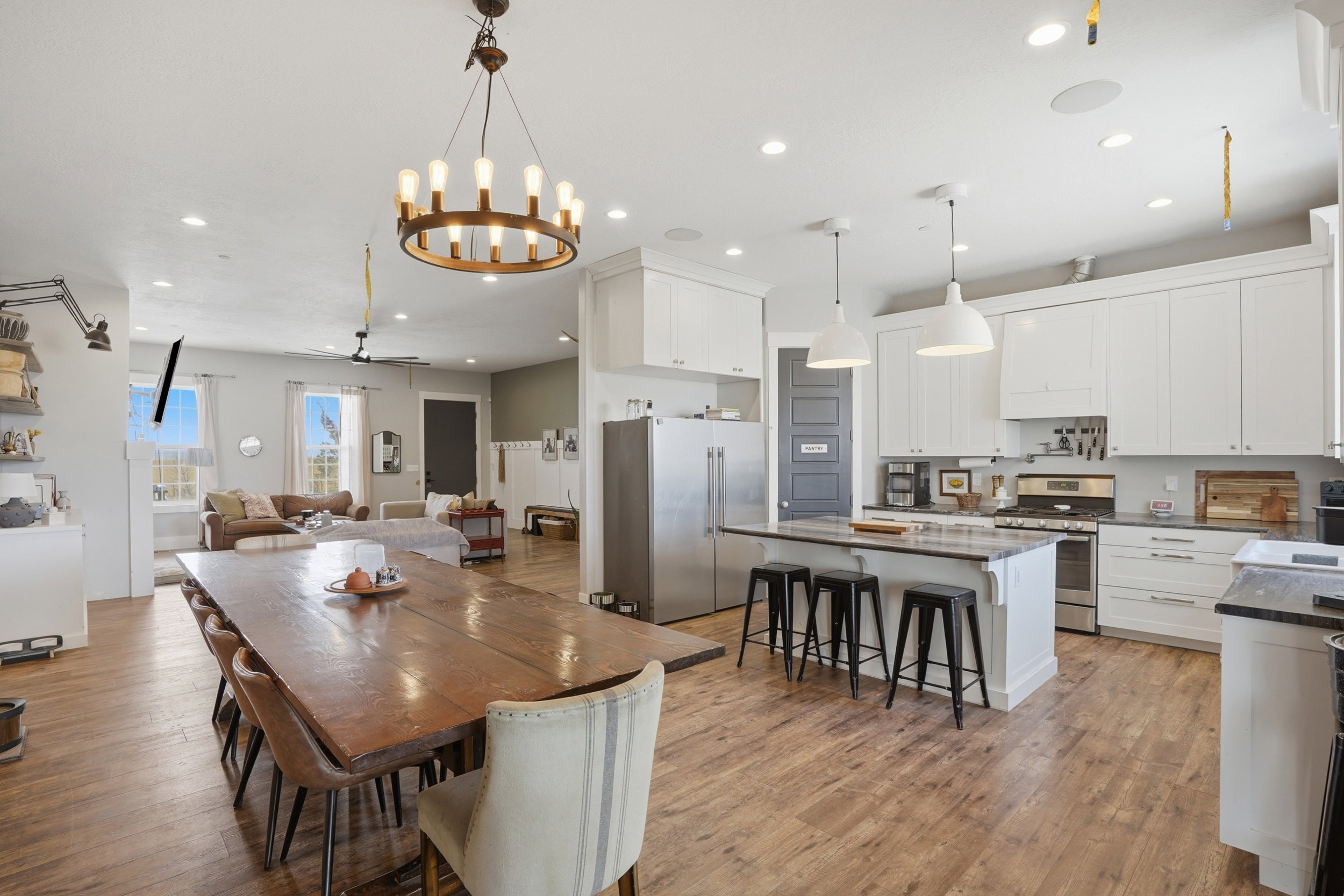Open-concept kitchen and dining area featuring wood-finish flooring, white cabinetry, a kitchen island with seating, stainless steel appliances, and recessed lighting