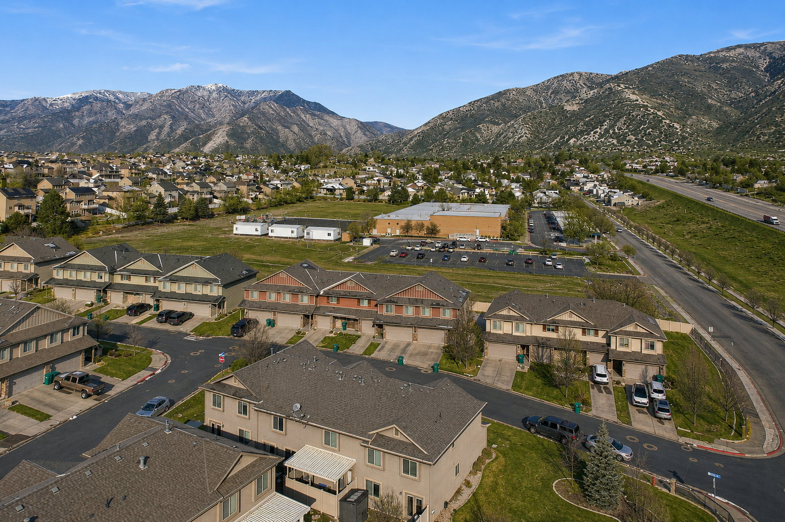 Panoramic aerial perspective showcasing a residential community against a backdrop of mountainous terrain