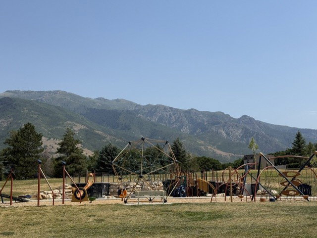 Expansive recreational area featuring multiple play structures and a natural mountain backdrop