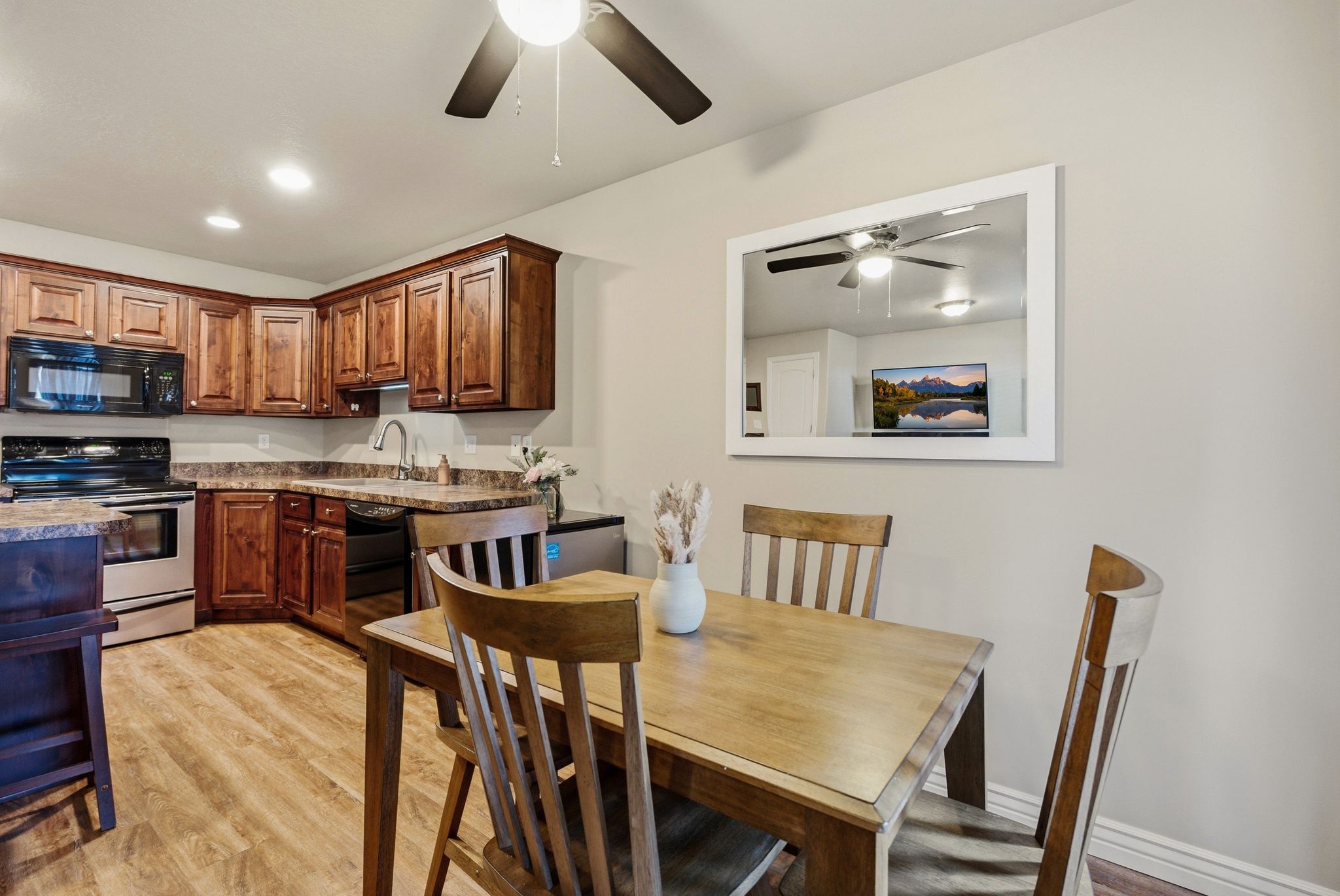 Kitchen with black appliances, light wood finished floors, a ceiling fan, recessed lighting, and wood finish cabinets