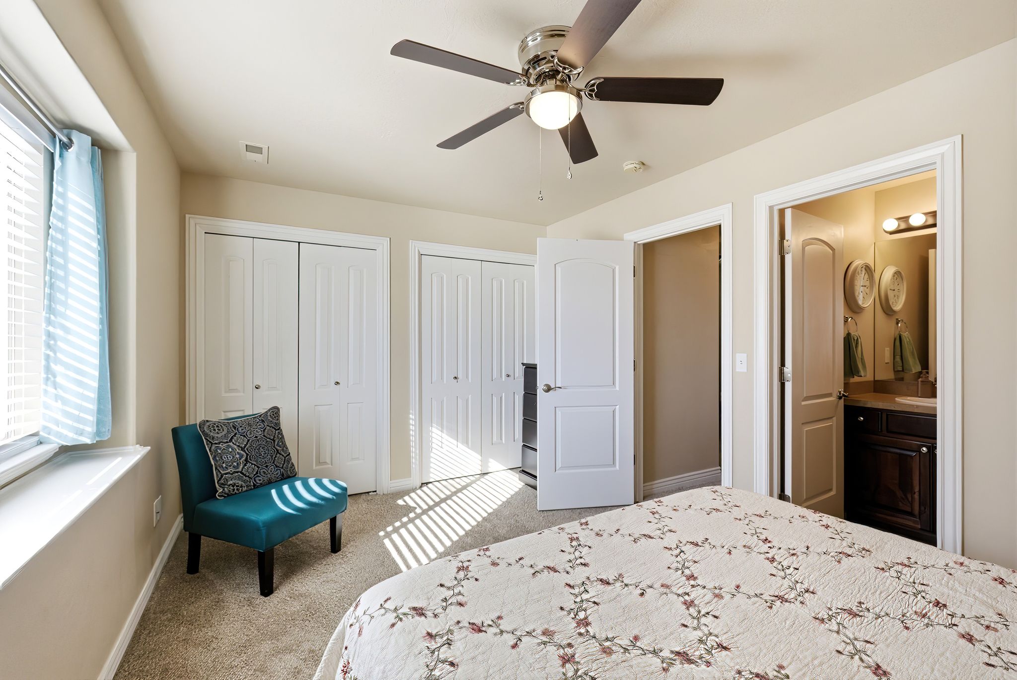 Primary Bedroom with multiple closets, light carpet, a ceiling fan, and connected bathroom