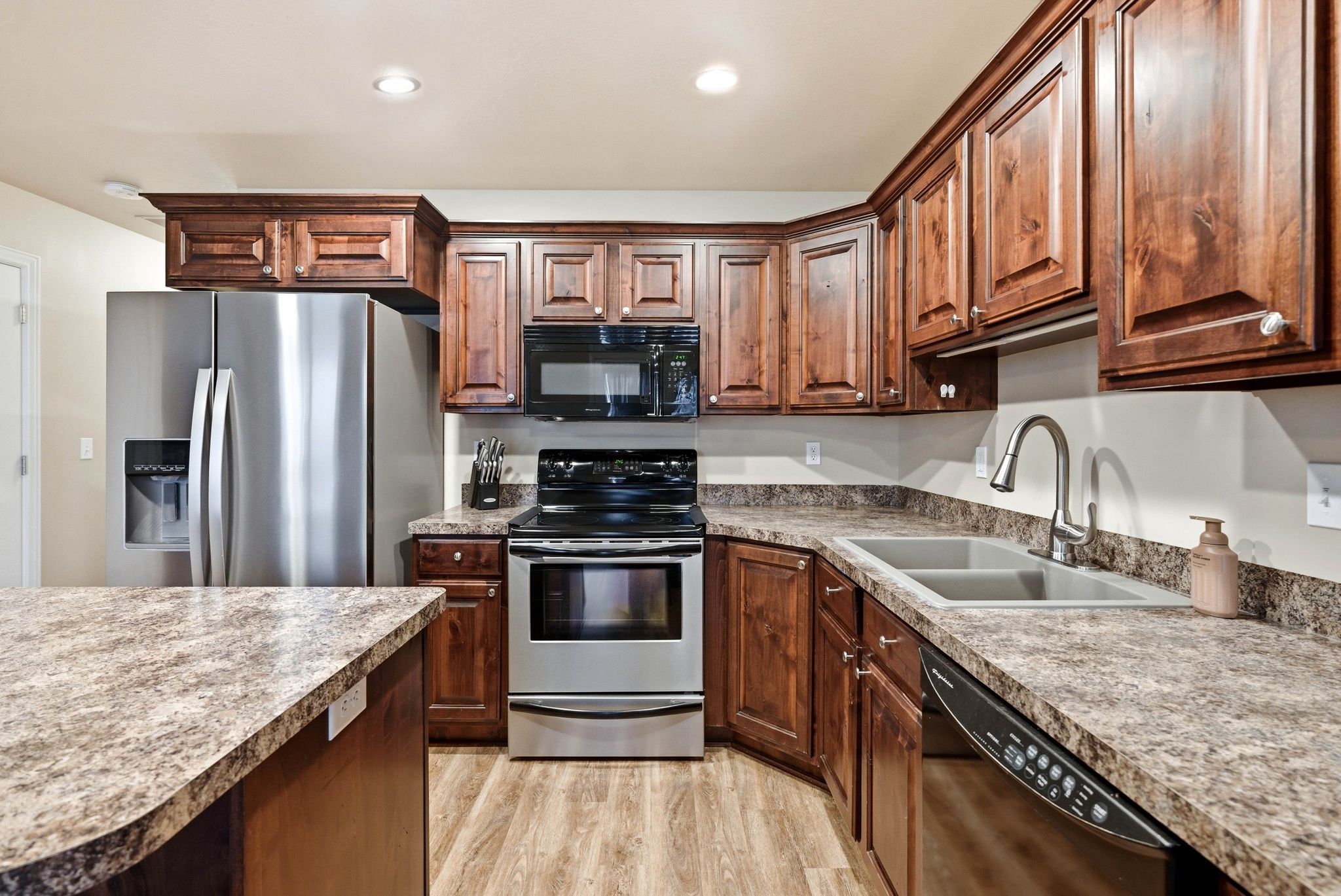Kitchen featuring black appliances, light wood-style floors, recessed lighting, and light countertops