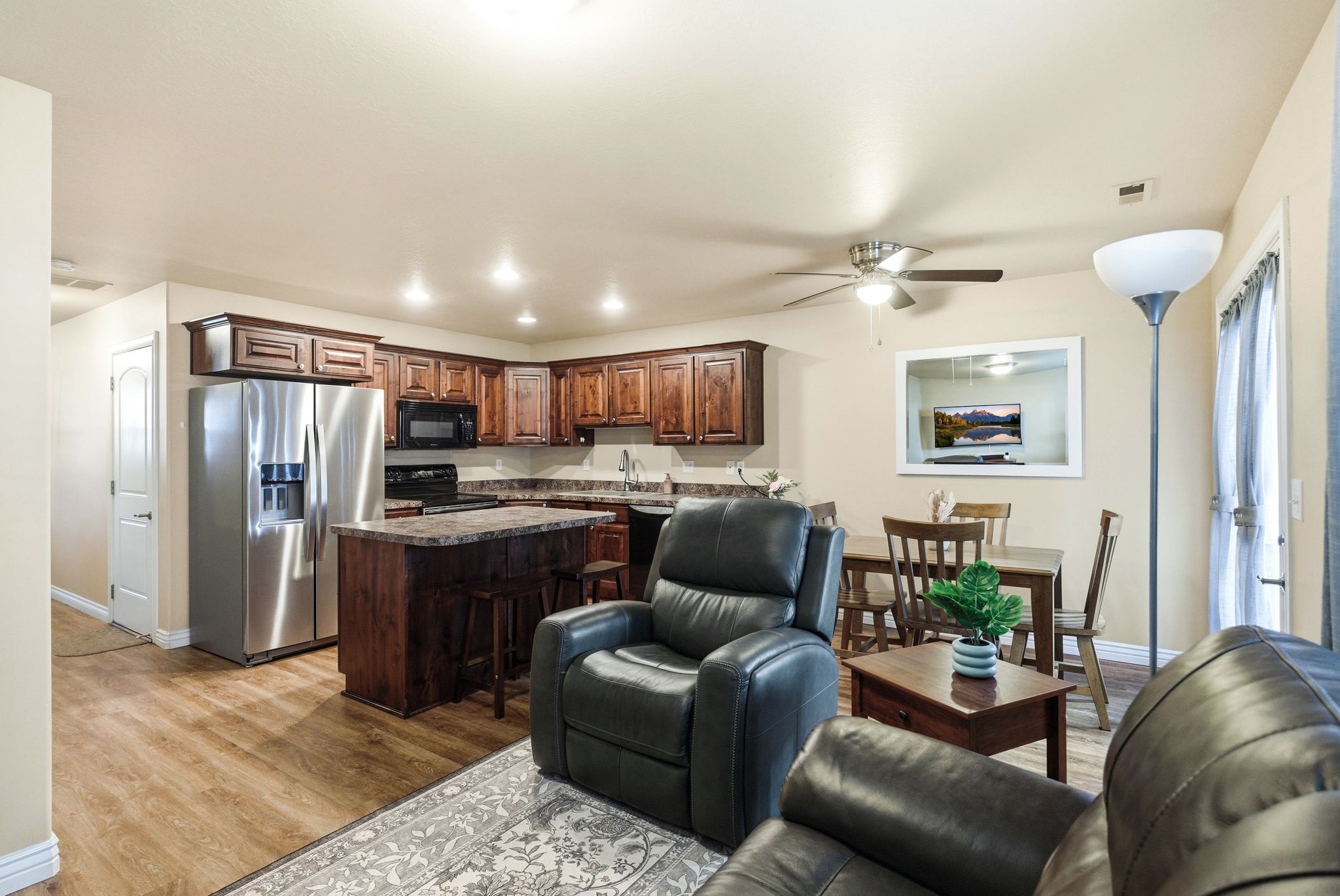 Kitchen featuring black appliances, a kitchen island, ceiling fan, light wood-style floors, and dark wood finish cabinets