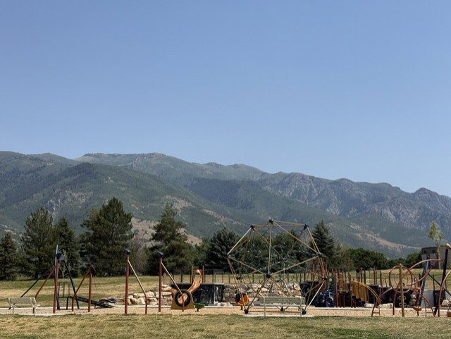 Community park with a variety of playground equipment, including climbing structures and swings