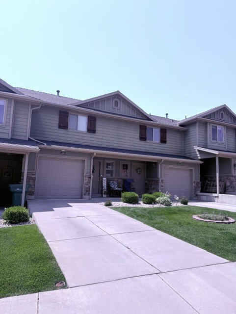 Townhome exterior with light green siding and dark shutters