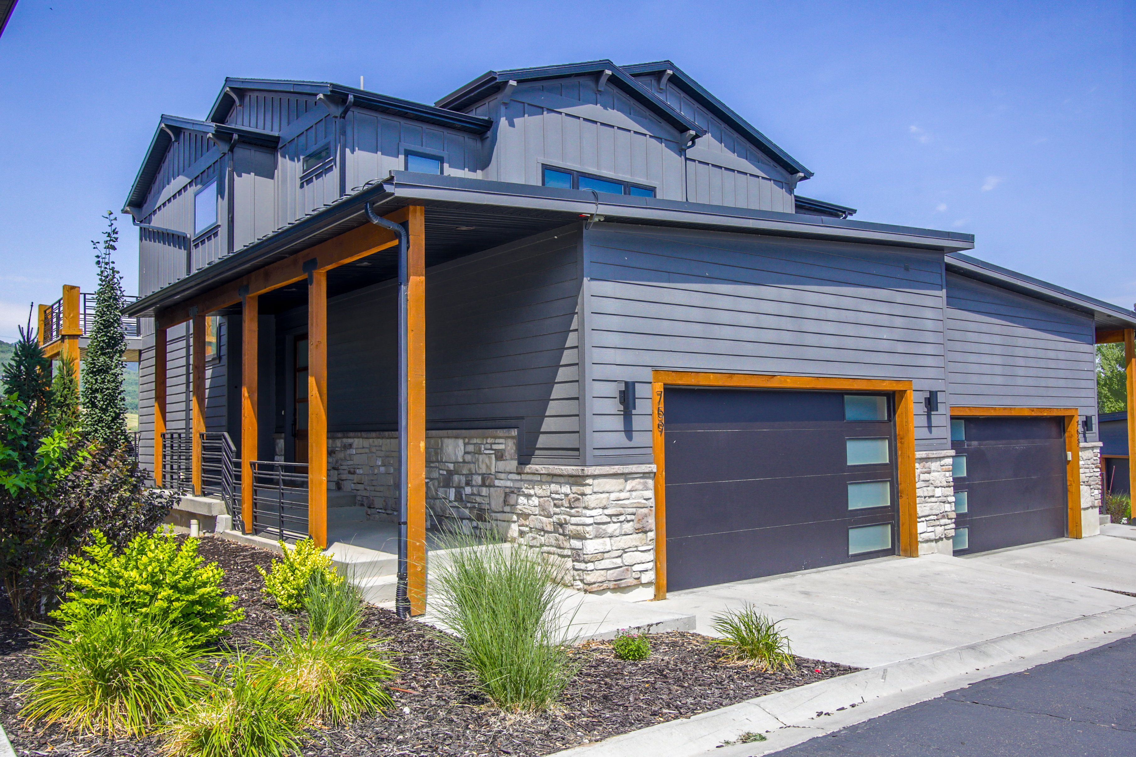 Modern architectural design featuring gray horizontal siding, vertical paneling, and stone accents