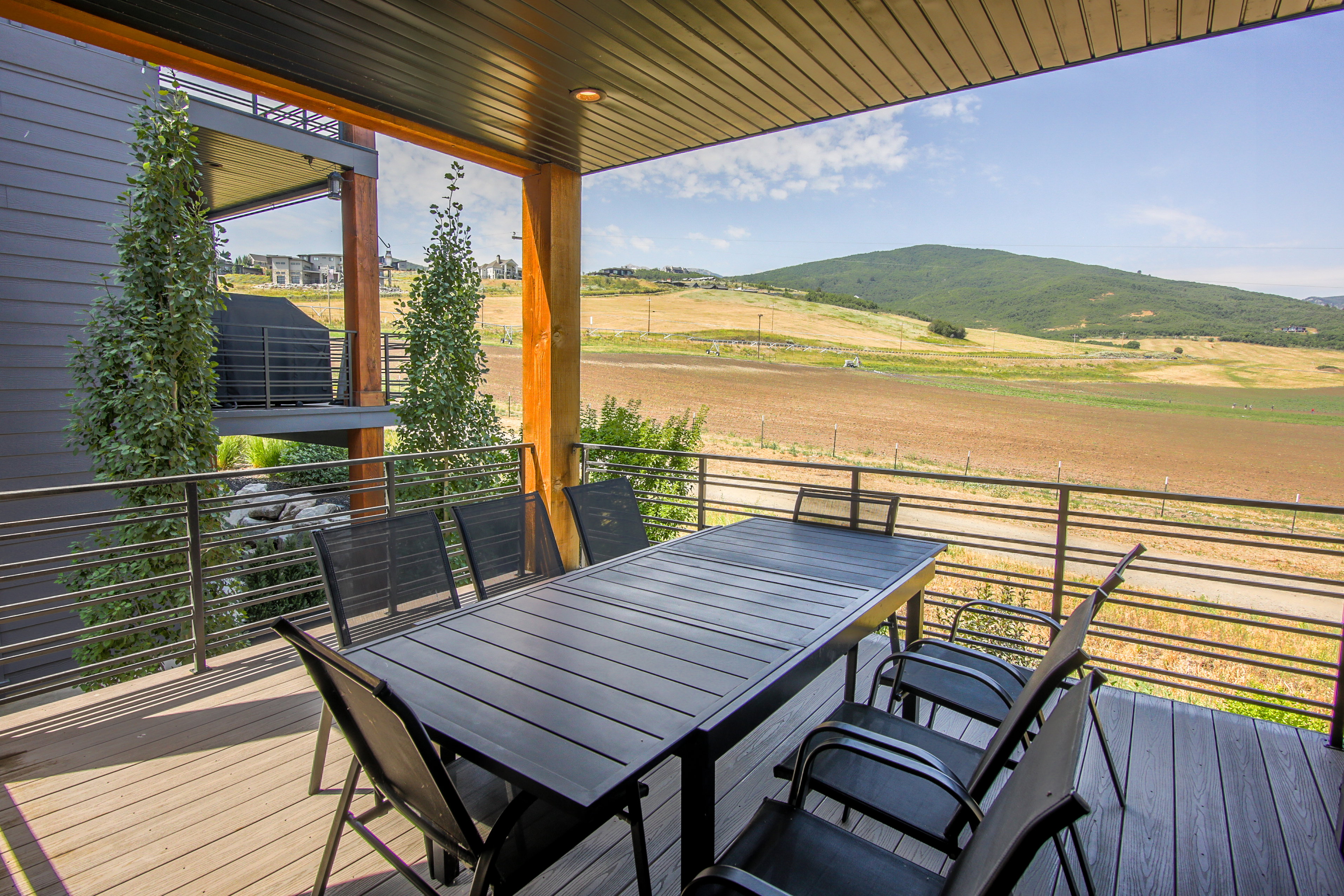 Covered outdoor deck with composite decking, horizontal railing, and wood support beams