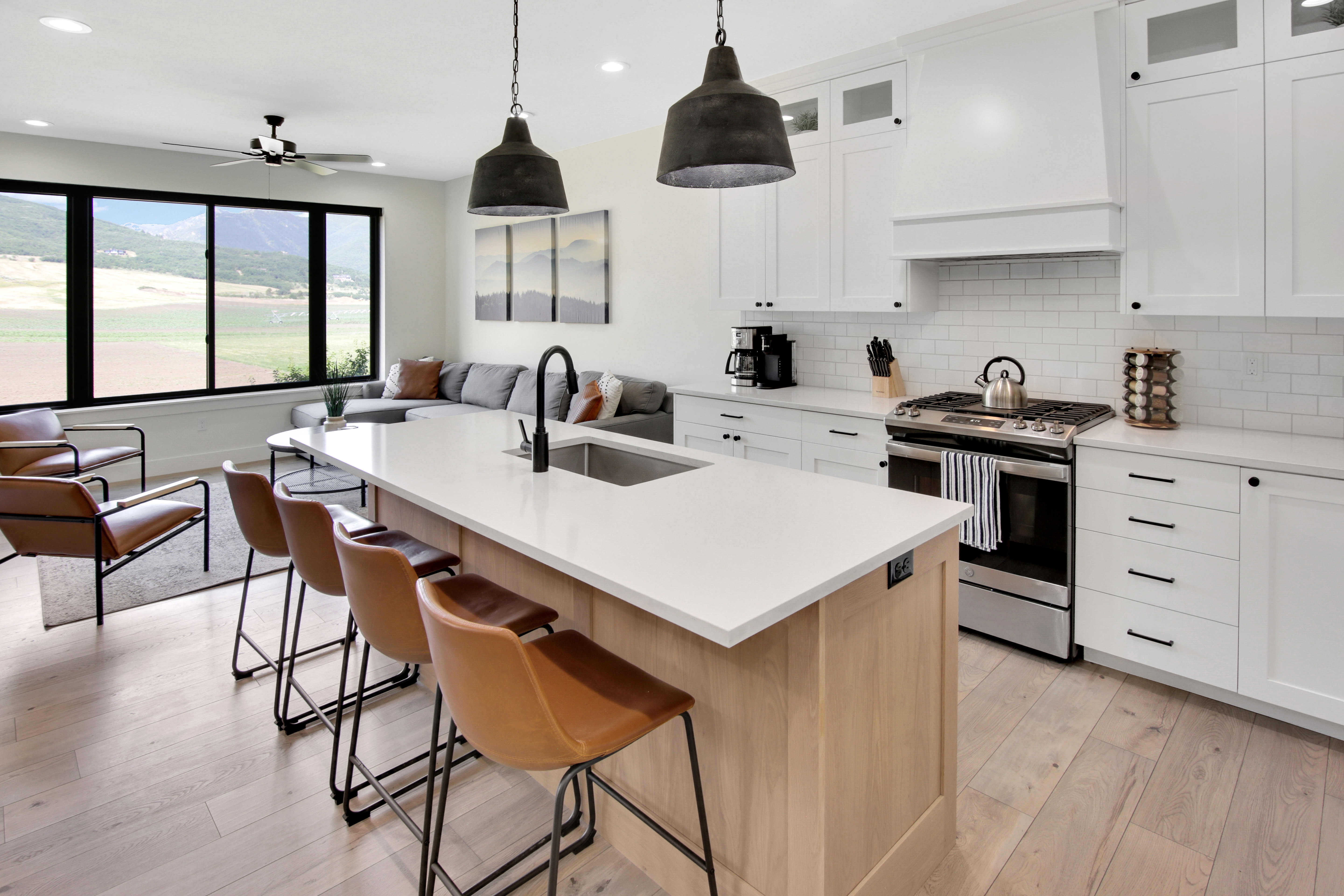 Open-concept space featuring a kitchen island with seating, stainless steel appliances, white subway tile backsplash, and wood-finish flooring