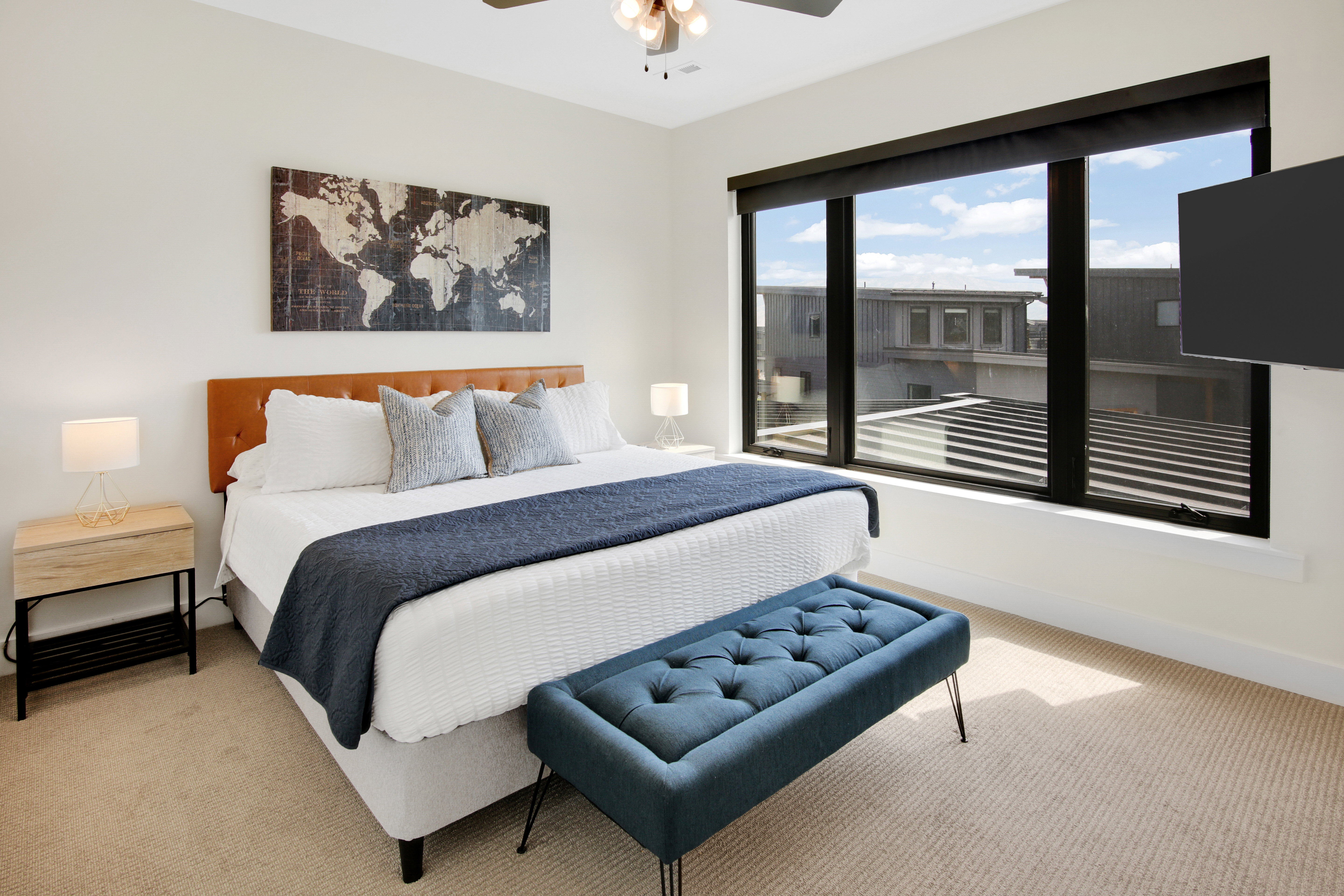 Room featuring a large window with dark trim, light-colored carpet flooring, a ceiling fan with integrated lighting, and white walls