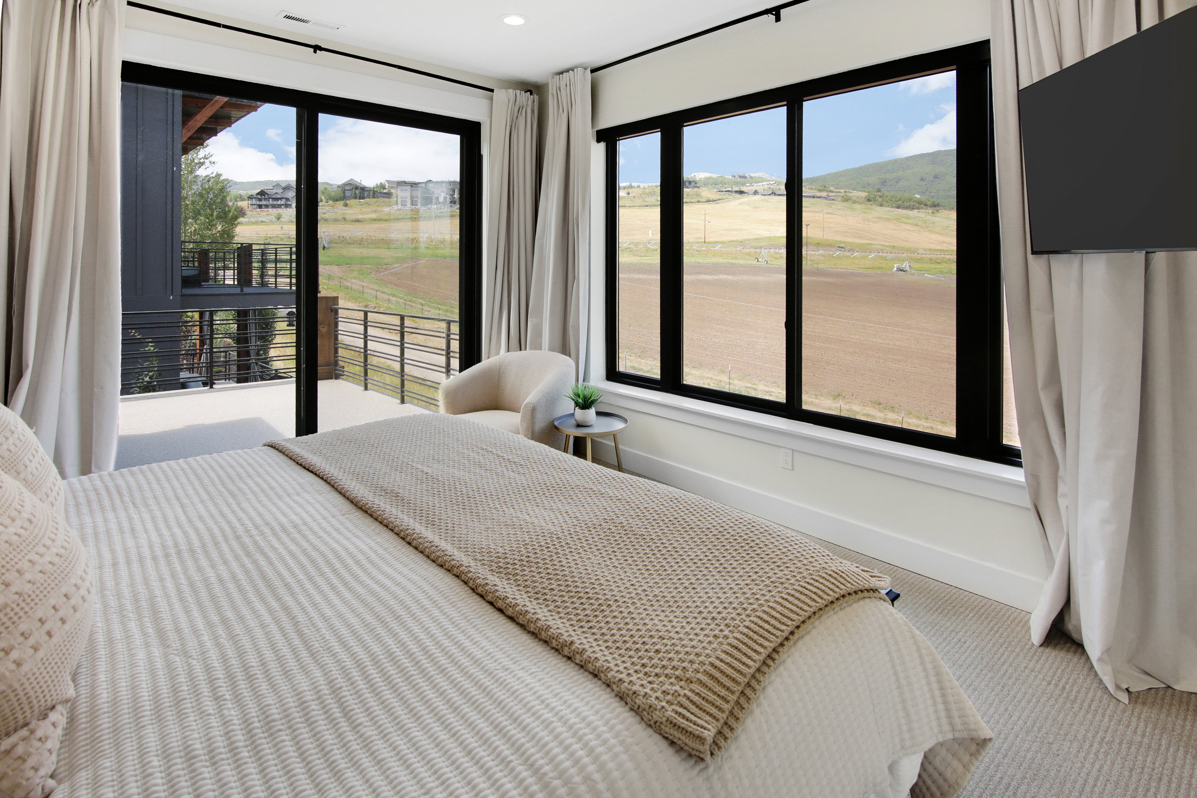 Bedroom featuring a large sliding glass door opening to an outdoor balcony with metal railings