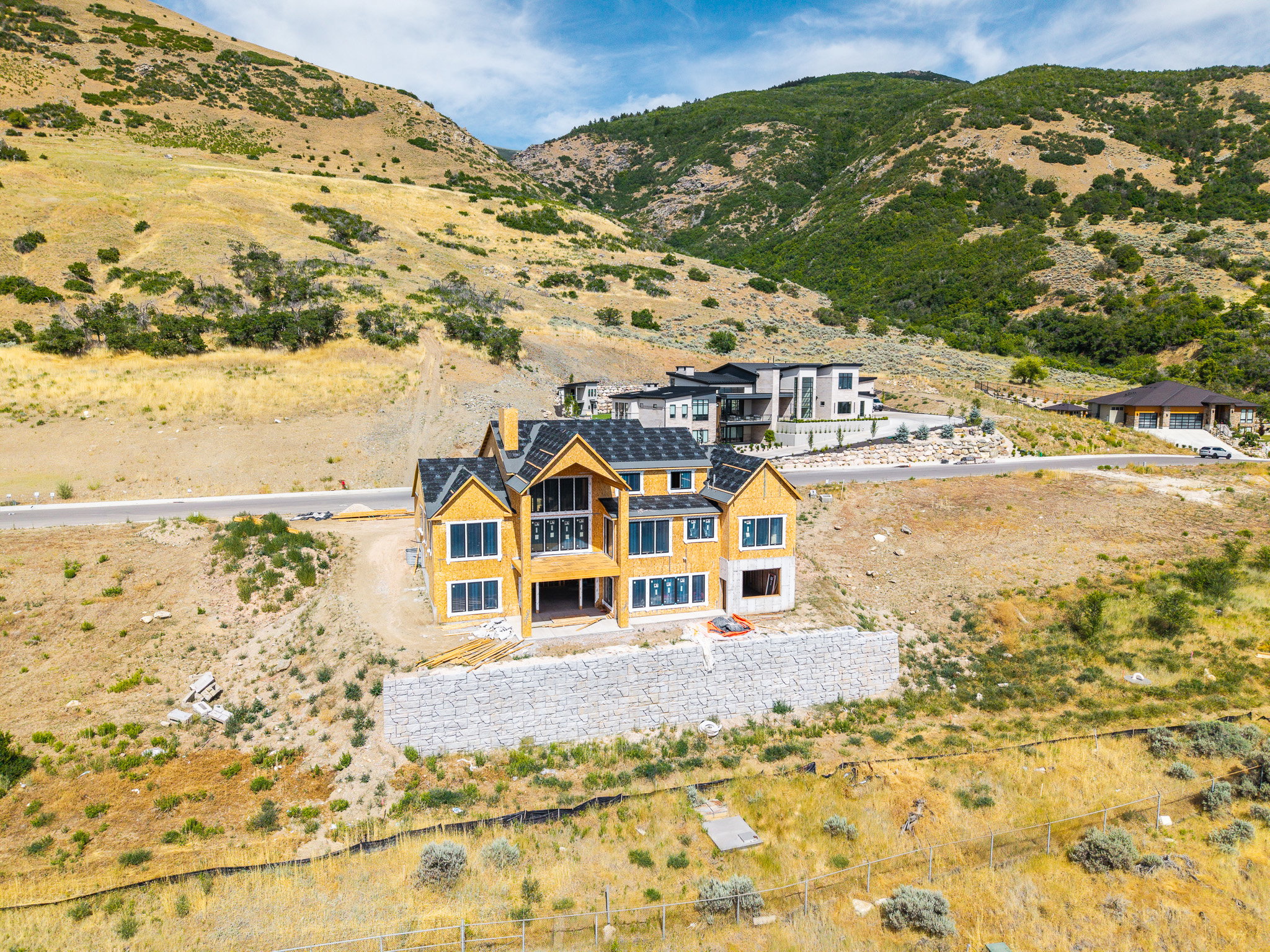 Newly constructed home featuring wood sheathing, multi-pane windows, and a dark shingle roof
