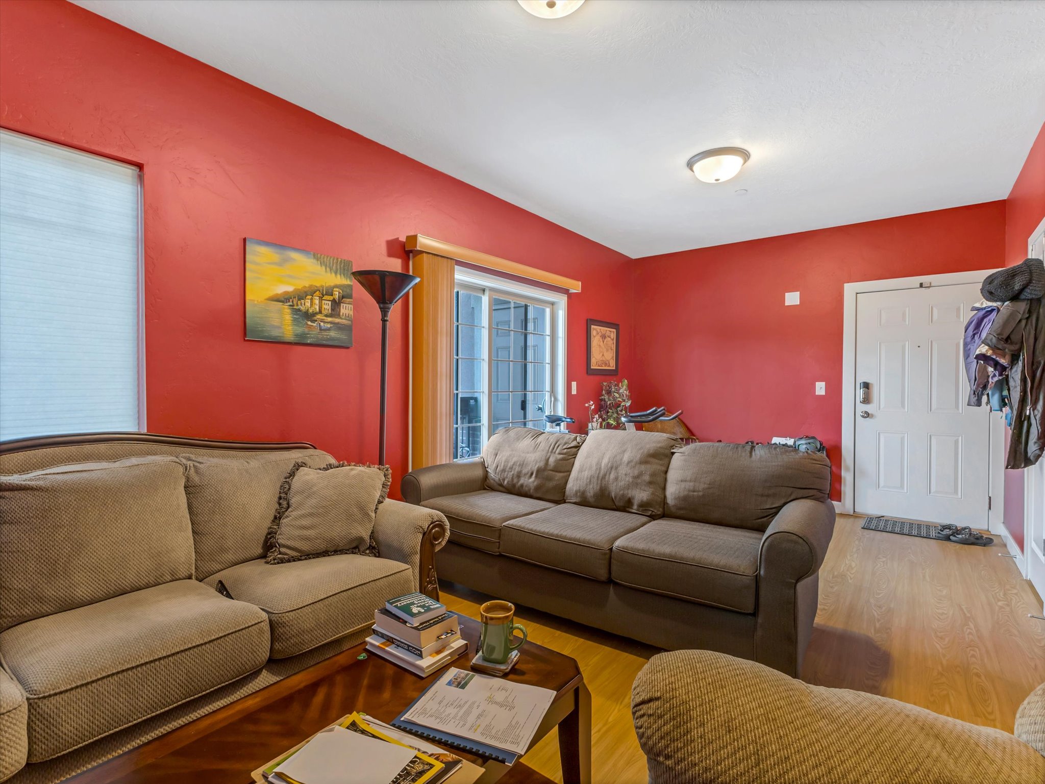 Living area featuring wood-finish flooring, a white paneled entry door, and a sliding glass door