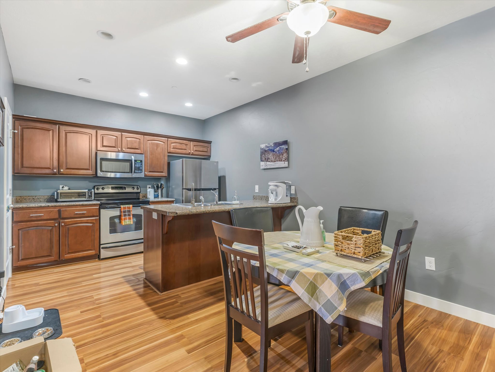 Kitchen featuring wood-finish flooring, dark wood cabinetry, stainless steel appliances, and a granite-style countertop