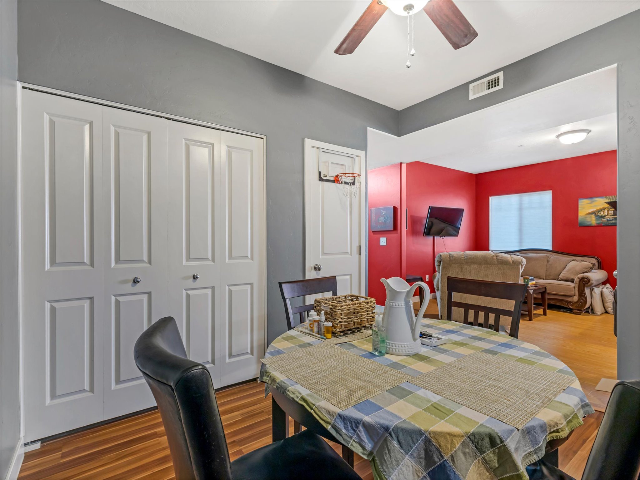 Dining area with wood-finish flooring, a ceiling fan, and white bi-fold closet doors