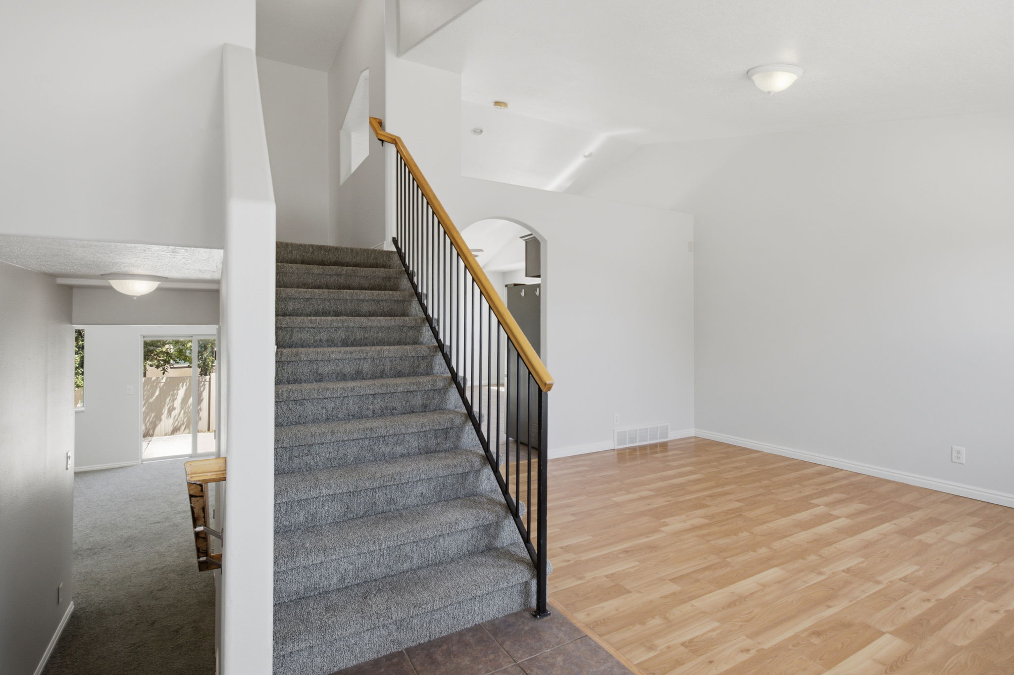 Carpeted staircase with black wrought iron spindles and a natural wood handrail