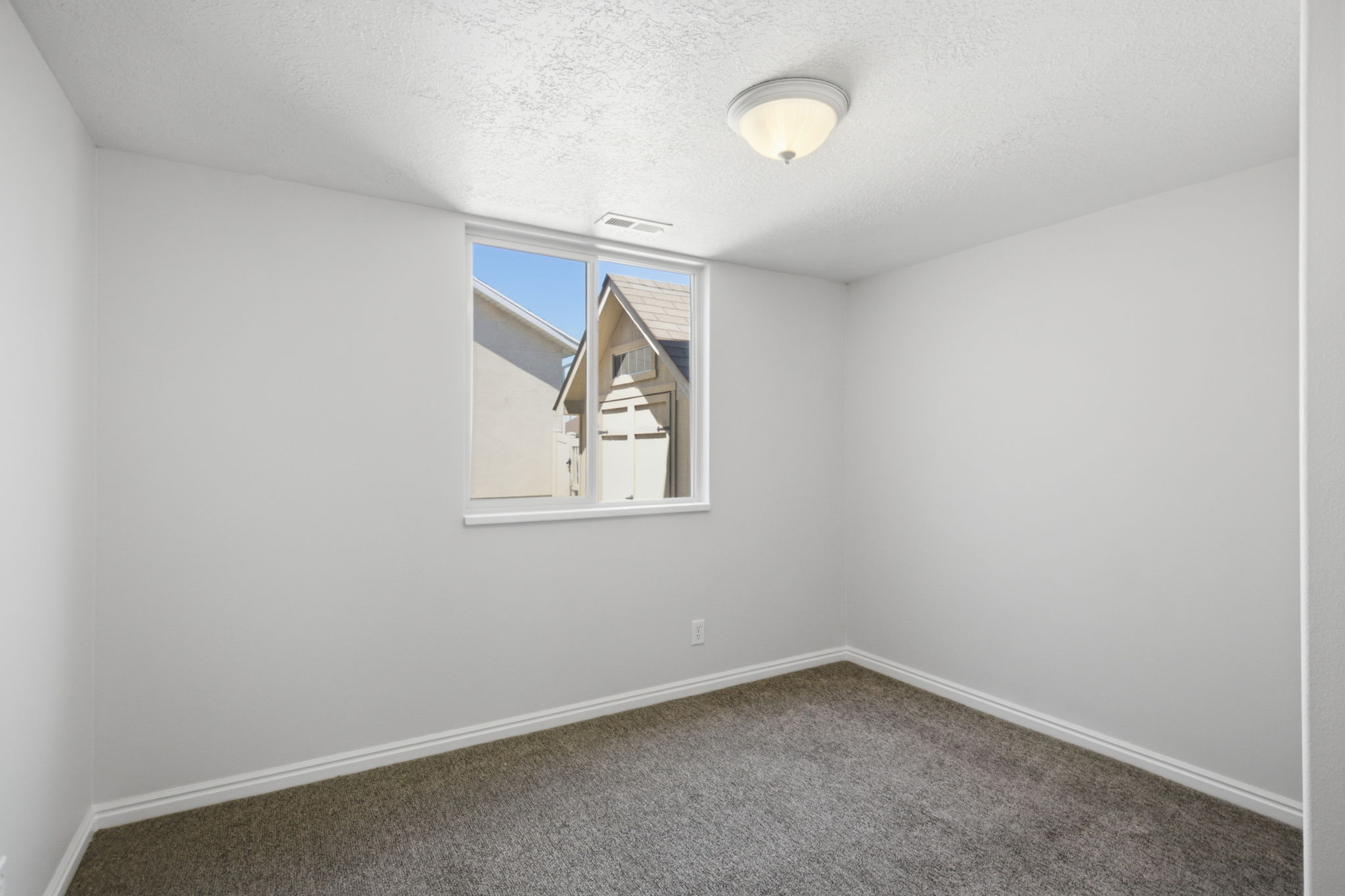 Neutral wall color, window with white trim, white baseboards, textured ceiling, and flush-mount ceiling light