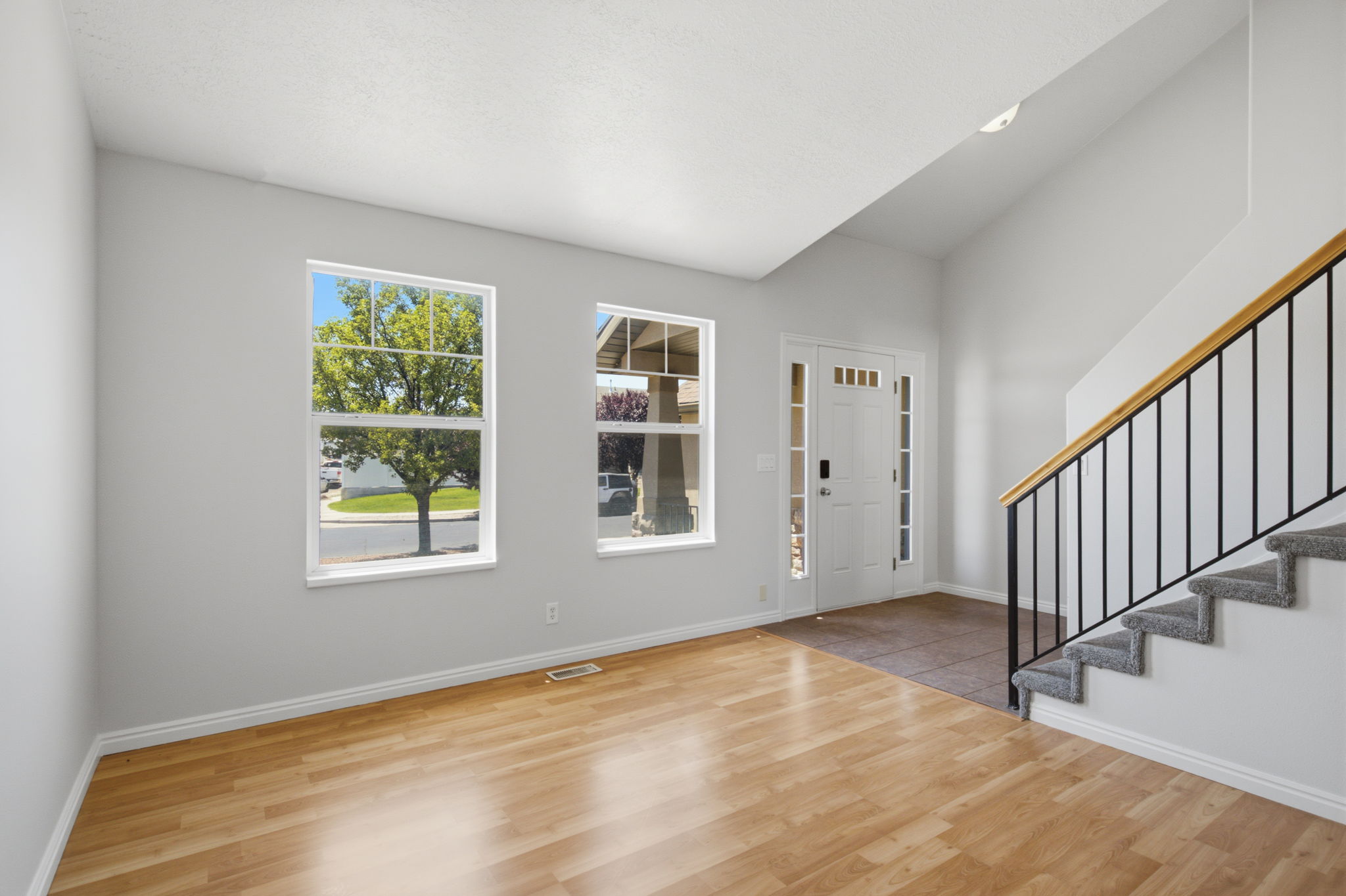 Bright entry space featuring wood-finish flooring, a two-story ceiling, and white trim throughout
