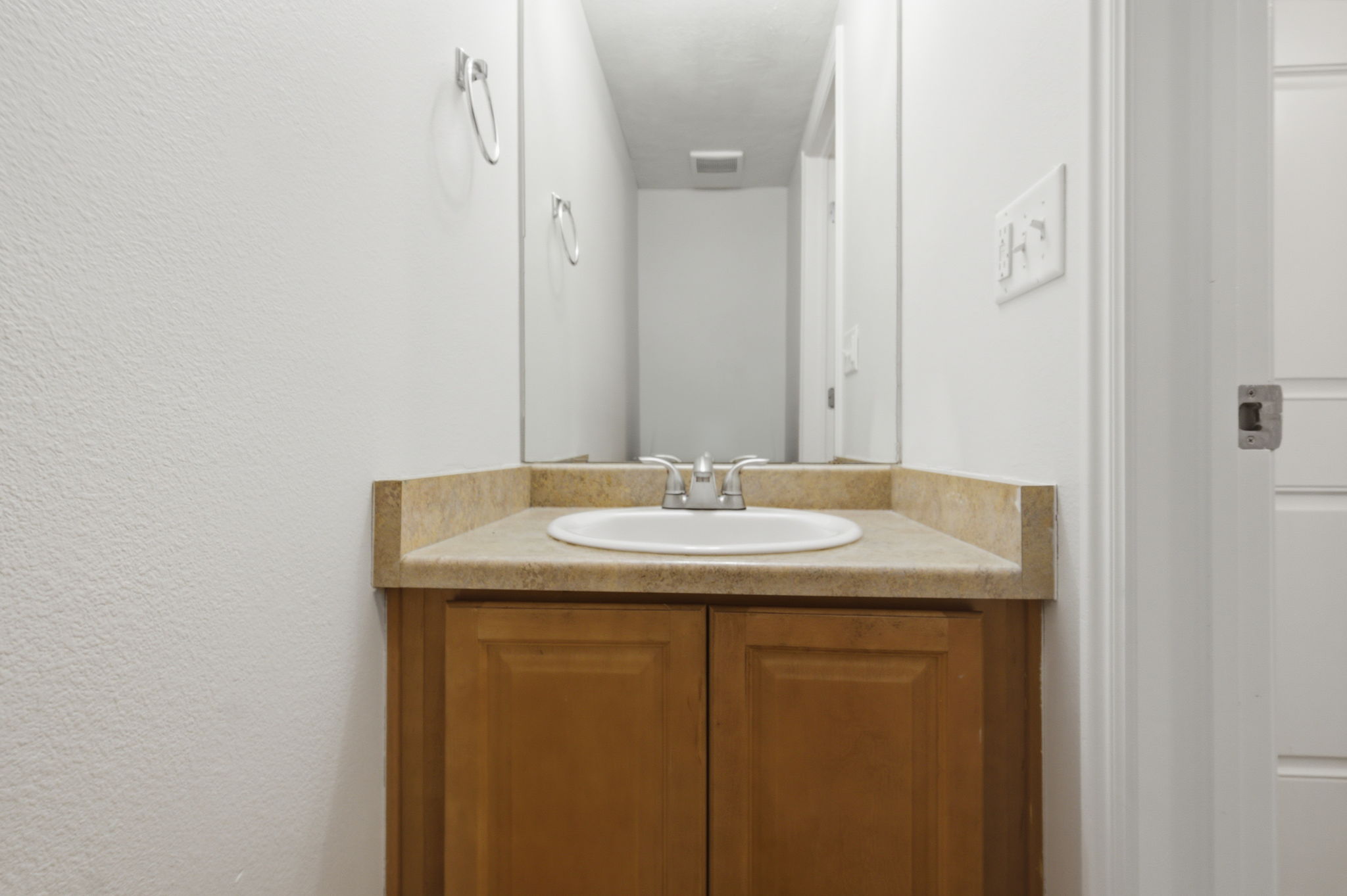 Bathroom vanity with a light wood-finish cabinet and a light tan countertop