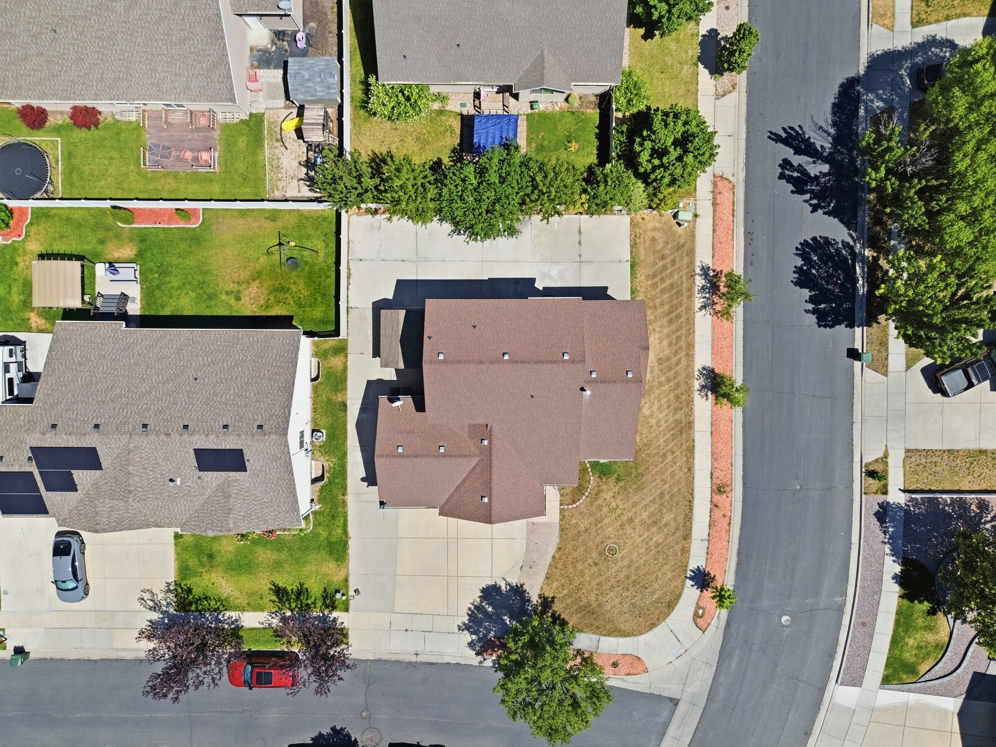 Single-family residence with a brown shingle roof, concrete driveway, and established trees