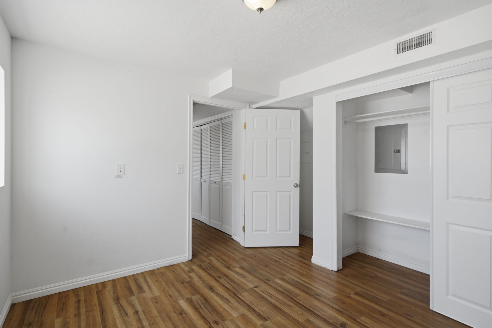 Room featuring wood-finish flooring, white baseboards, and a neutral wall palette
