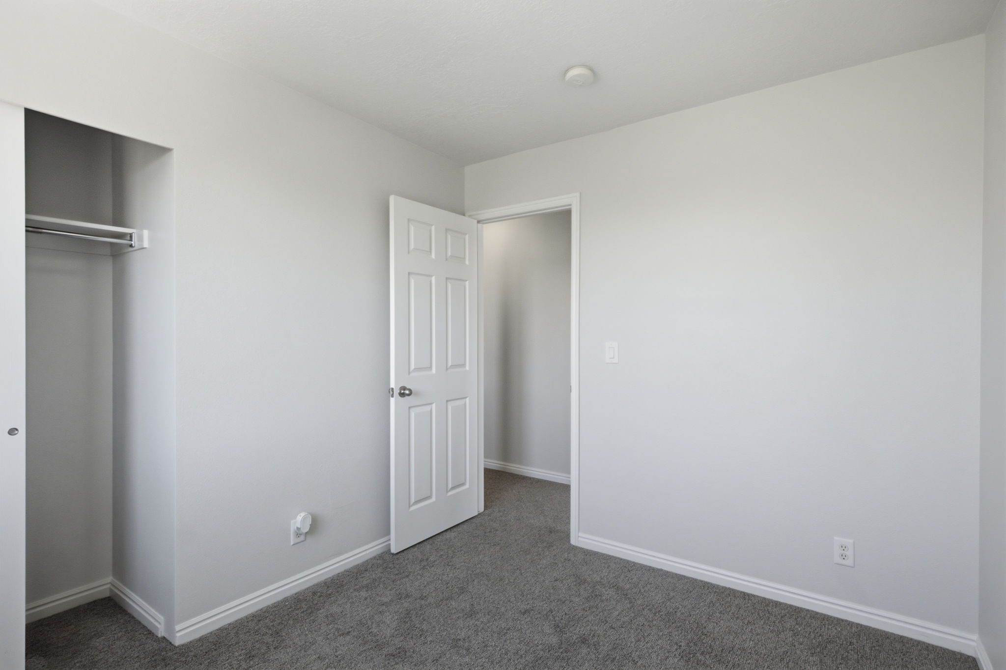 Light gray walls with white trim and a neutral gray carpet