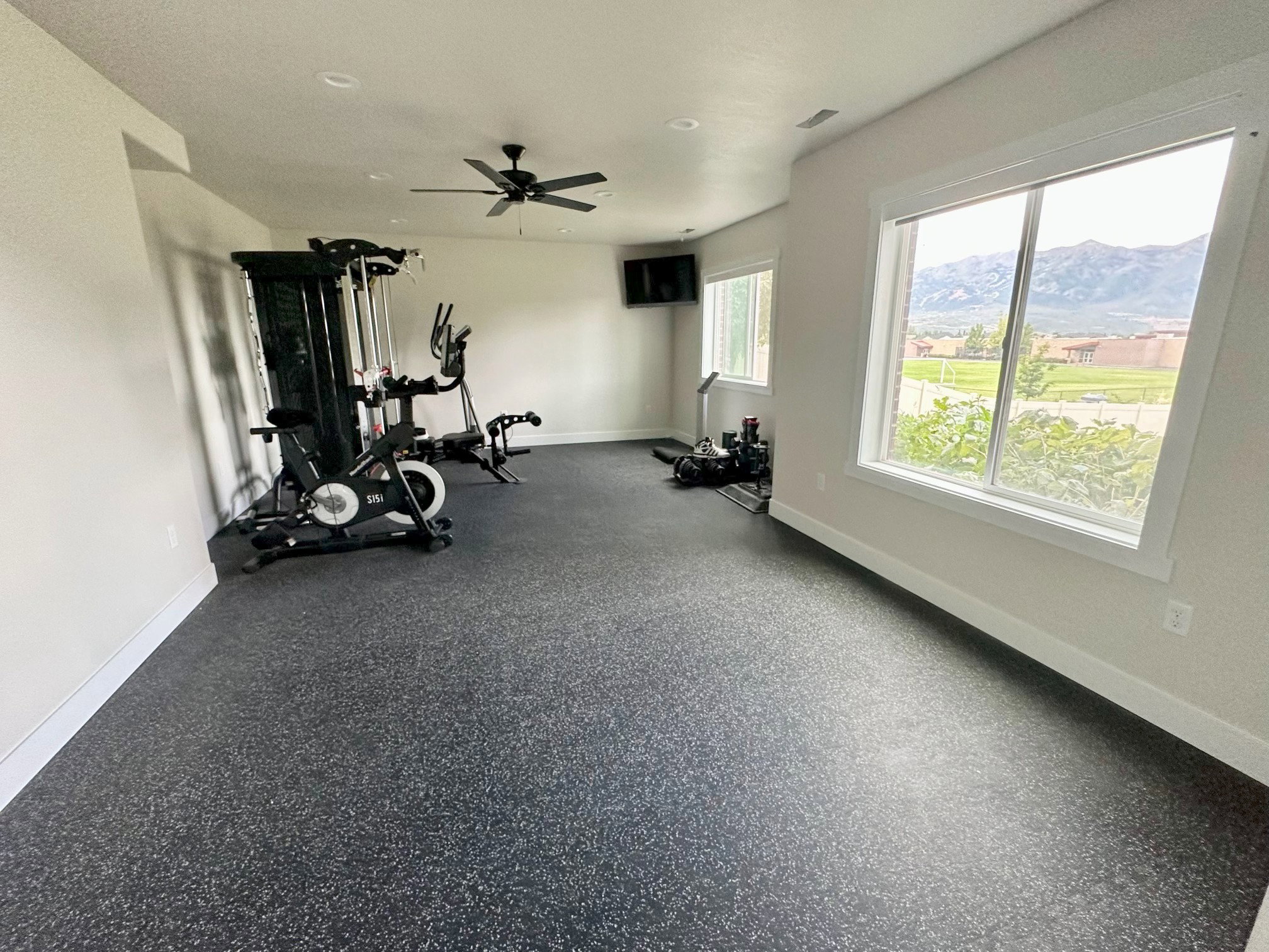 Spacious room featuring durable speckled flooring, recessed lighting, and a ceiling fan