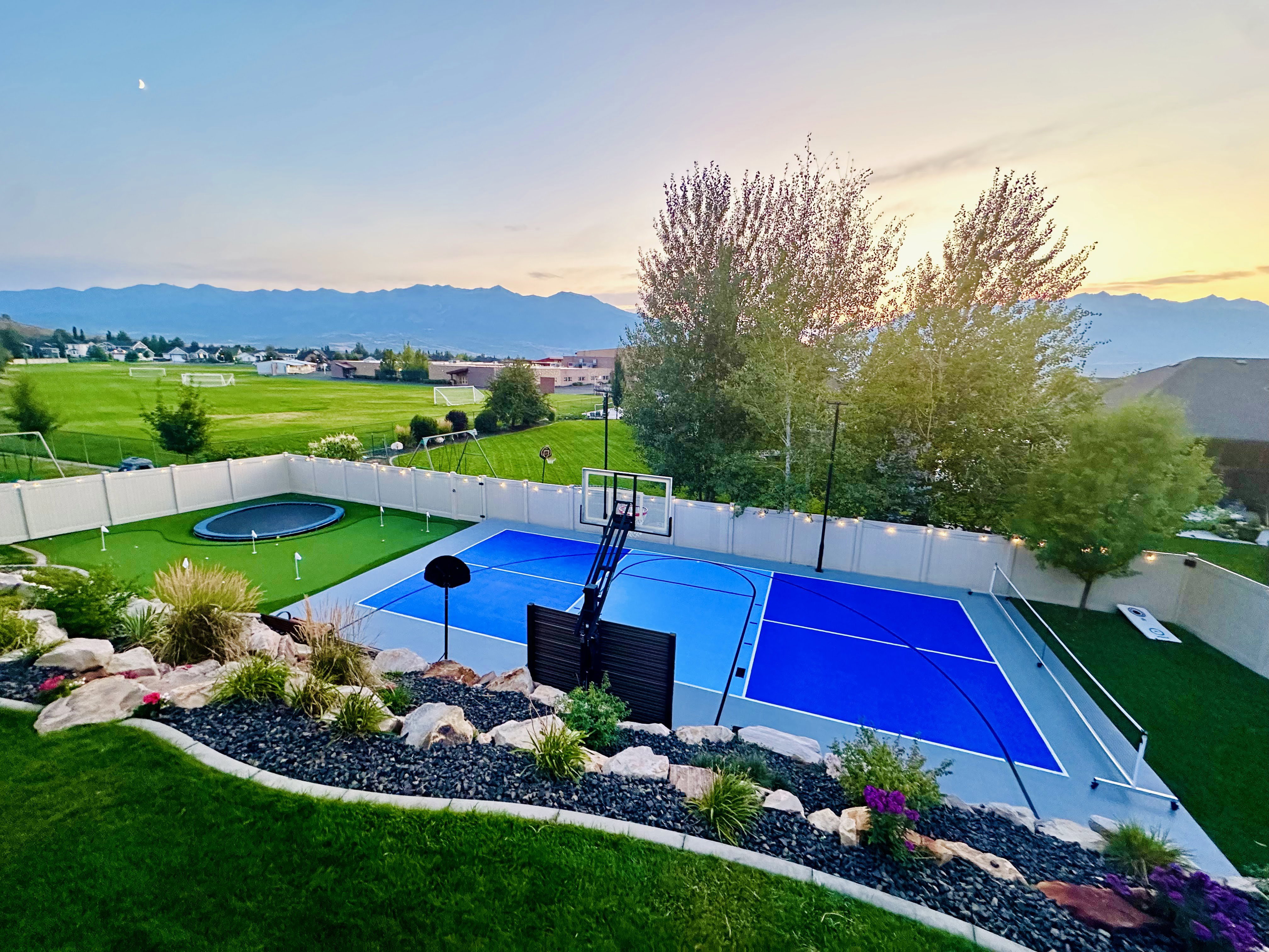 Multi-sport court with vibrant blue surfacing and an integrated basketball hoop