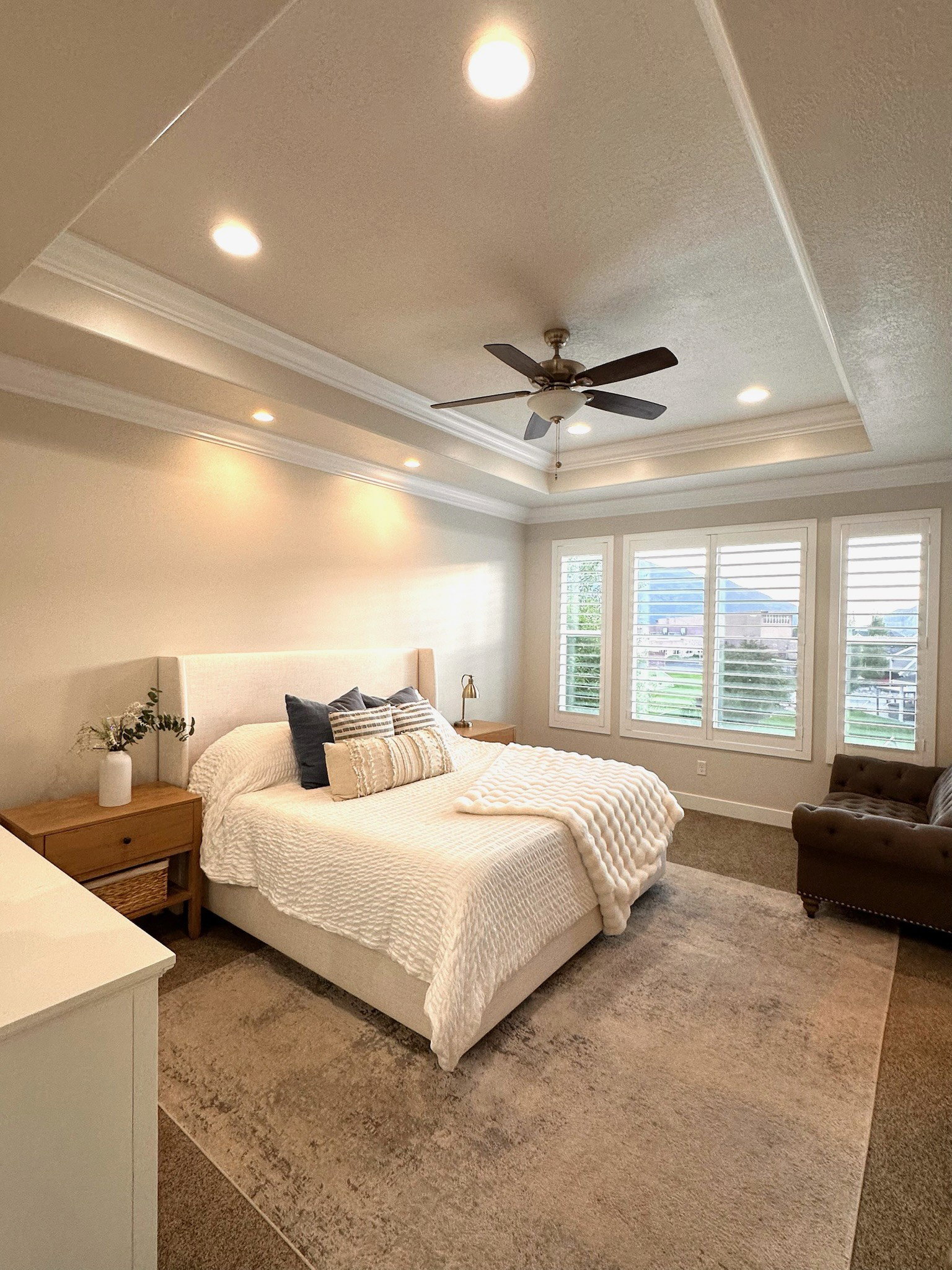 Spacious room featuring a tiered tray ceiling with recessed lighting and crown molding