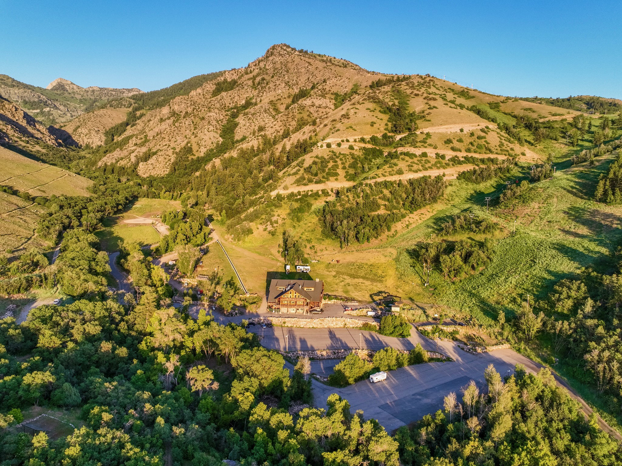 Expansive mountain property featuring a central lodge with a large paved parking area, surrounded by diverse natural terrain