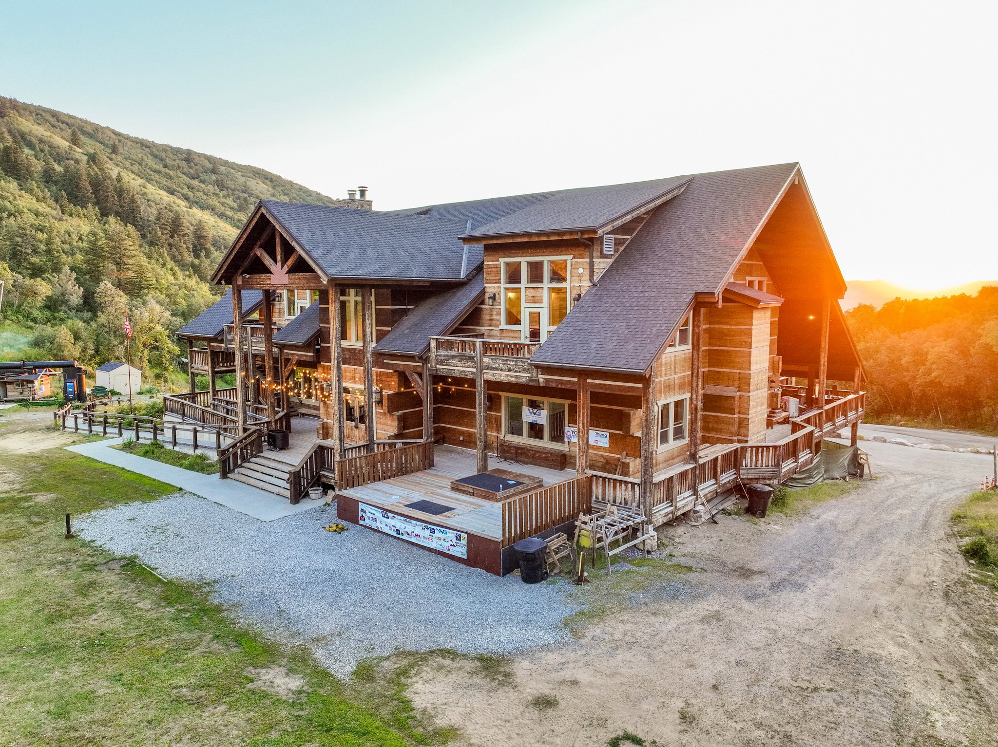Multi-level log cabin-style exterior with extensive decking, a covered entry porch, and a gravel driveway