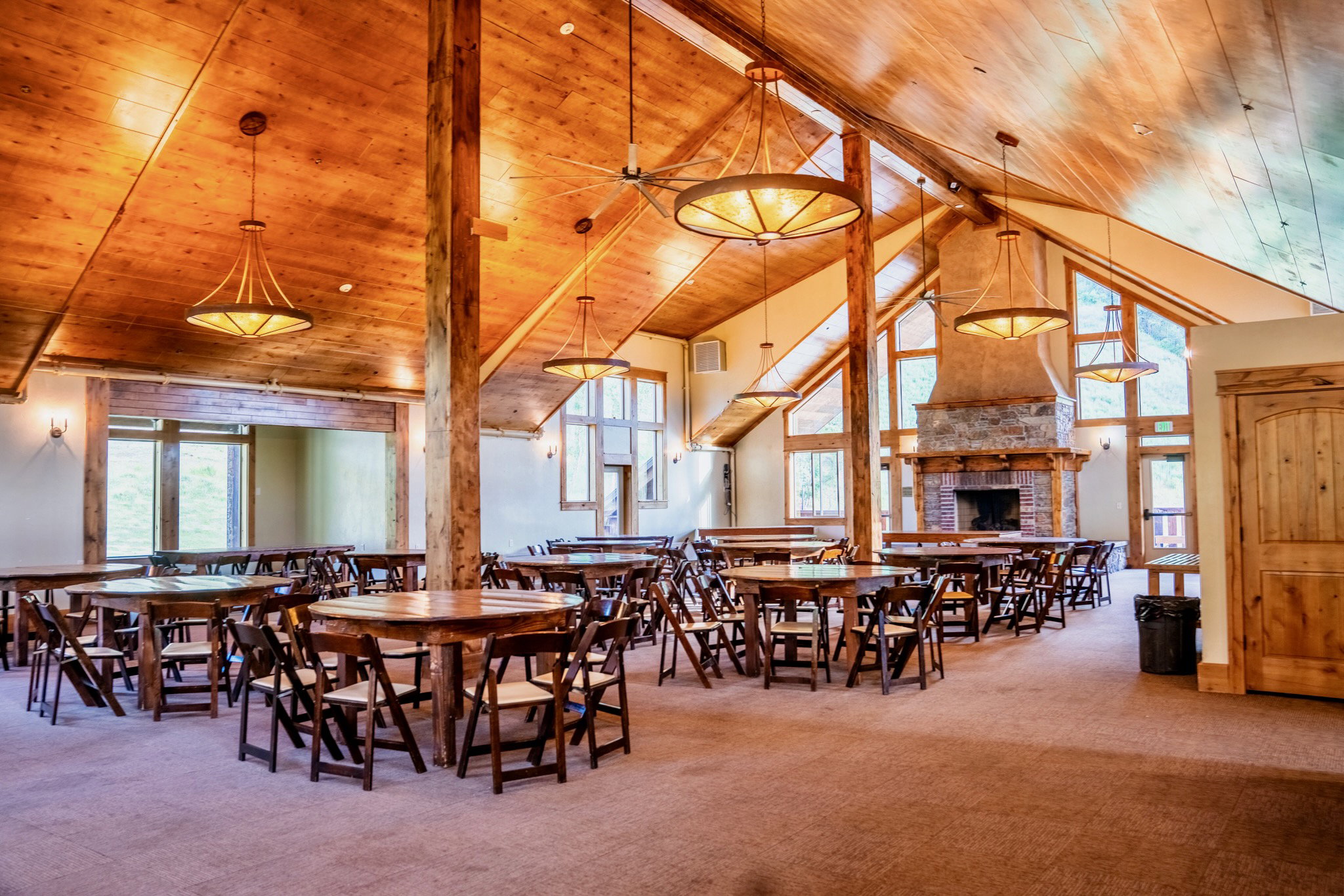 Vaulted wood-finish ceiling with exposed beams, illuminated by multiple decorative pendant lights and sconces