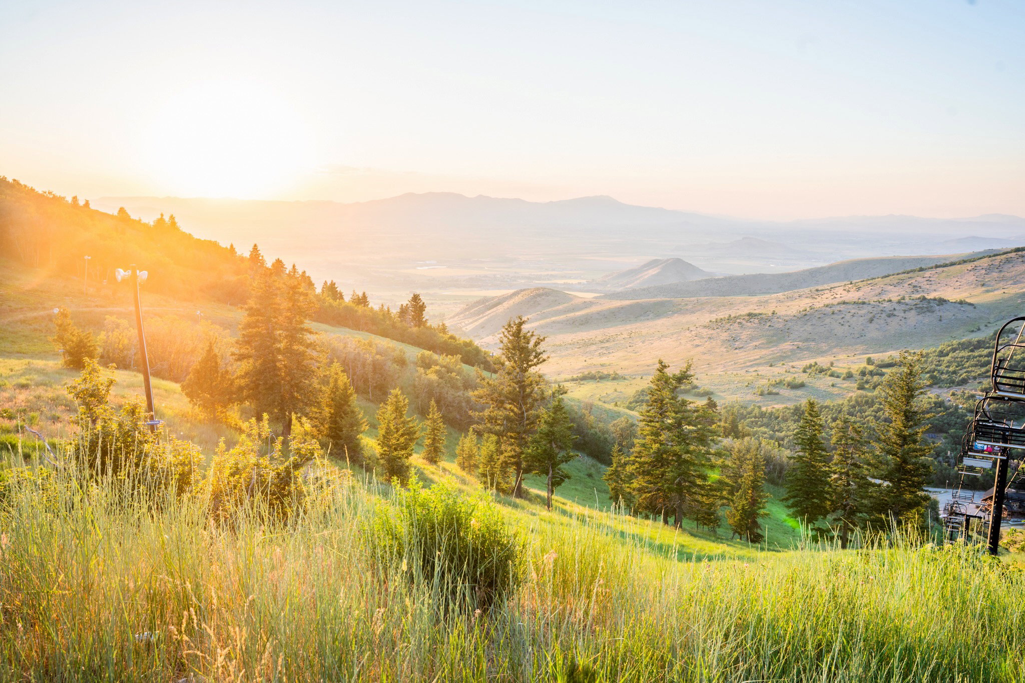 Expansive mountain landscape featuring rolling hills and distant ranges under a bright sky