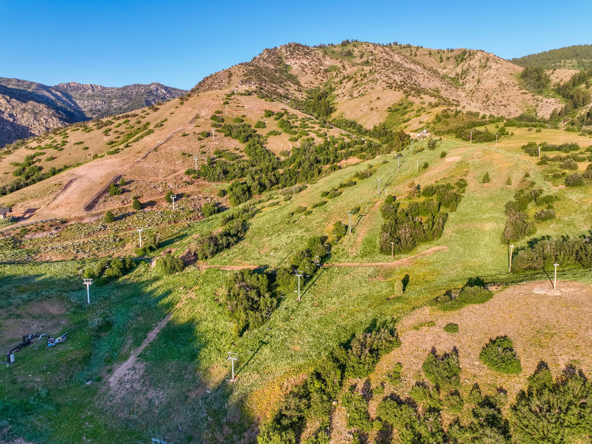 Expansive mountainous terrain with varied vegetation, including green slopes and scattered trees
