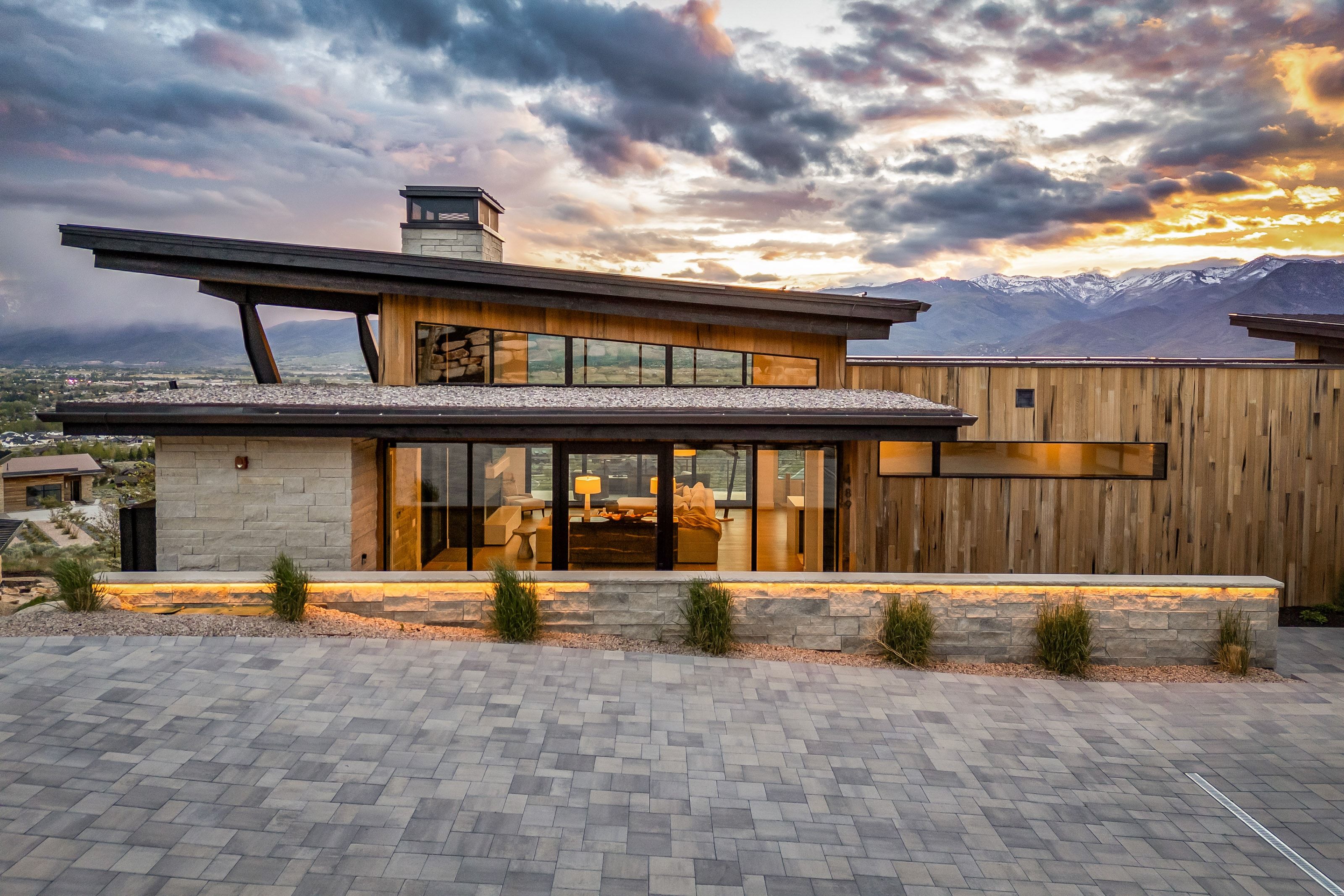Contemporary exterior showcasing a multi-pitched roofline and a combination of stone veneer and vertical wood siding