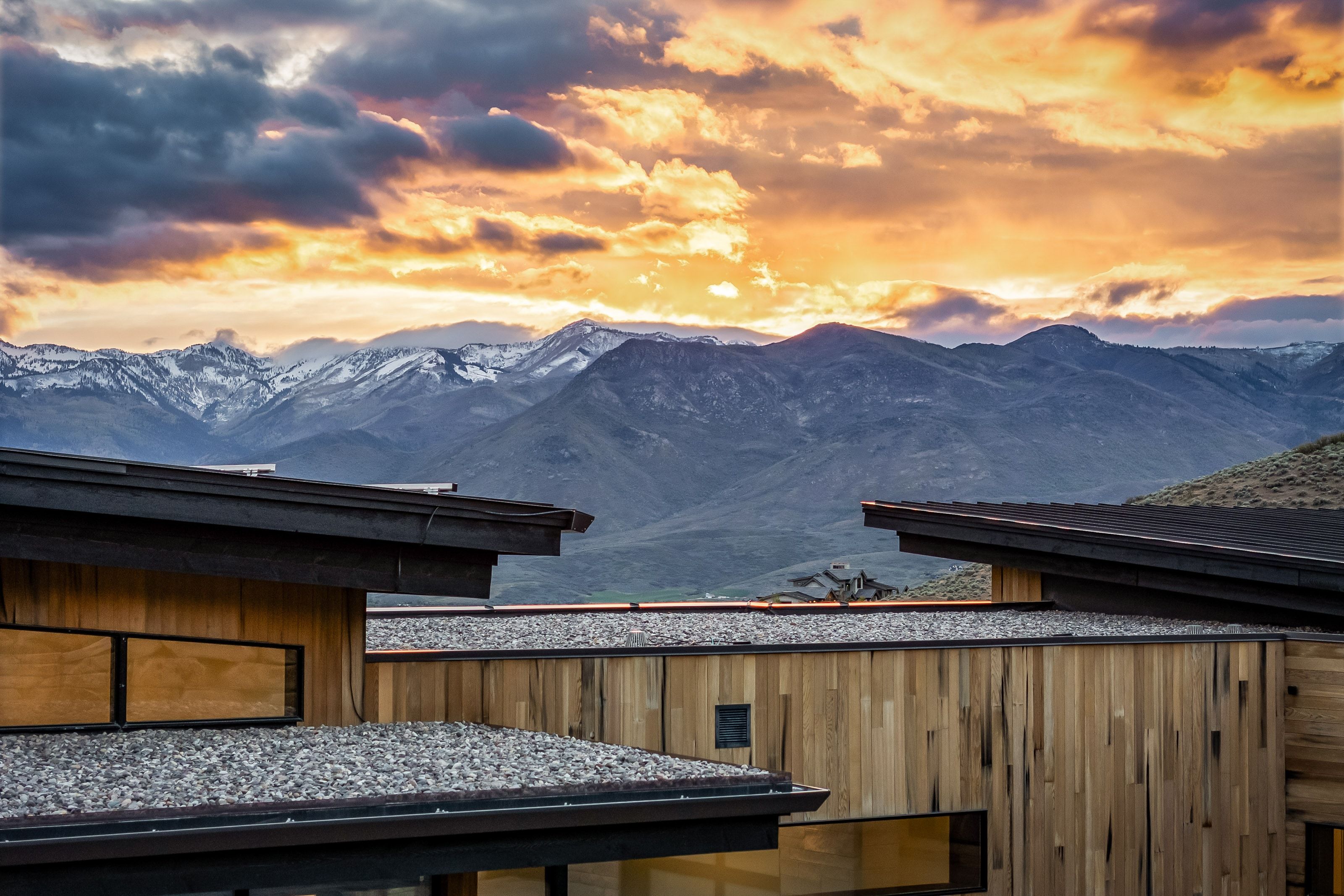 Contemporary architecture featuring flat roofs, natural wood siding, and expansive mountain scenery with snow-capped peaks
