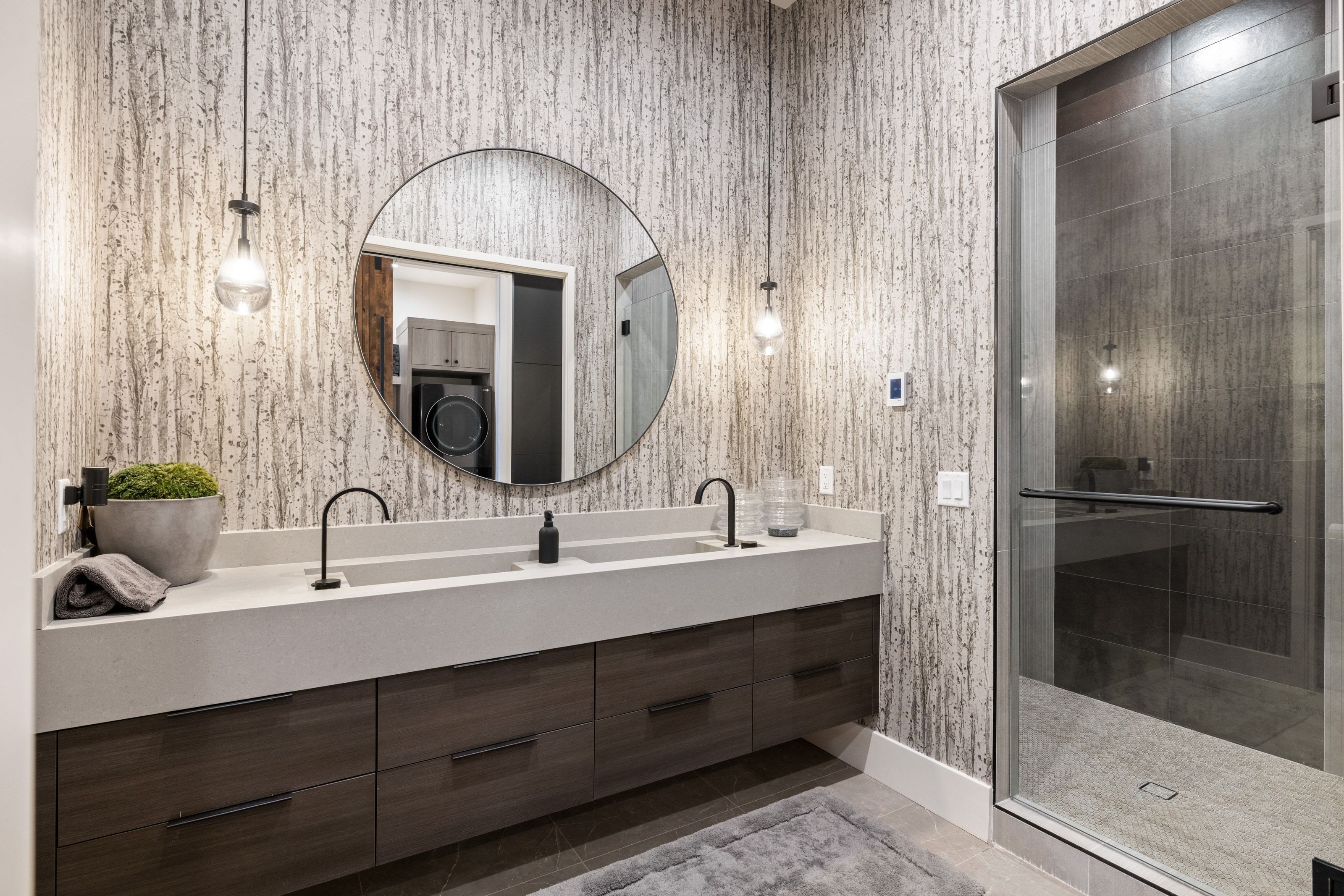 Bathroom featuring a dual-sink vanity with a light-toned countertop, dark wood-finish cabinetry, and matte black hardware