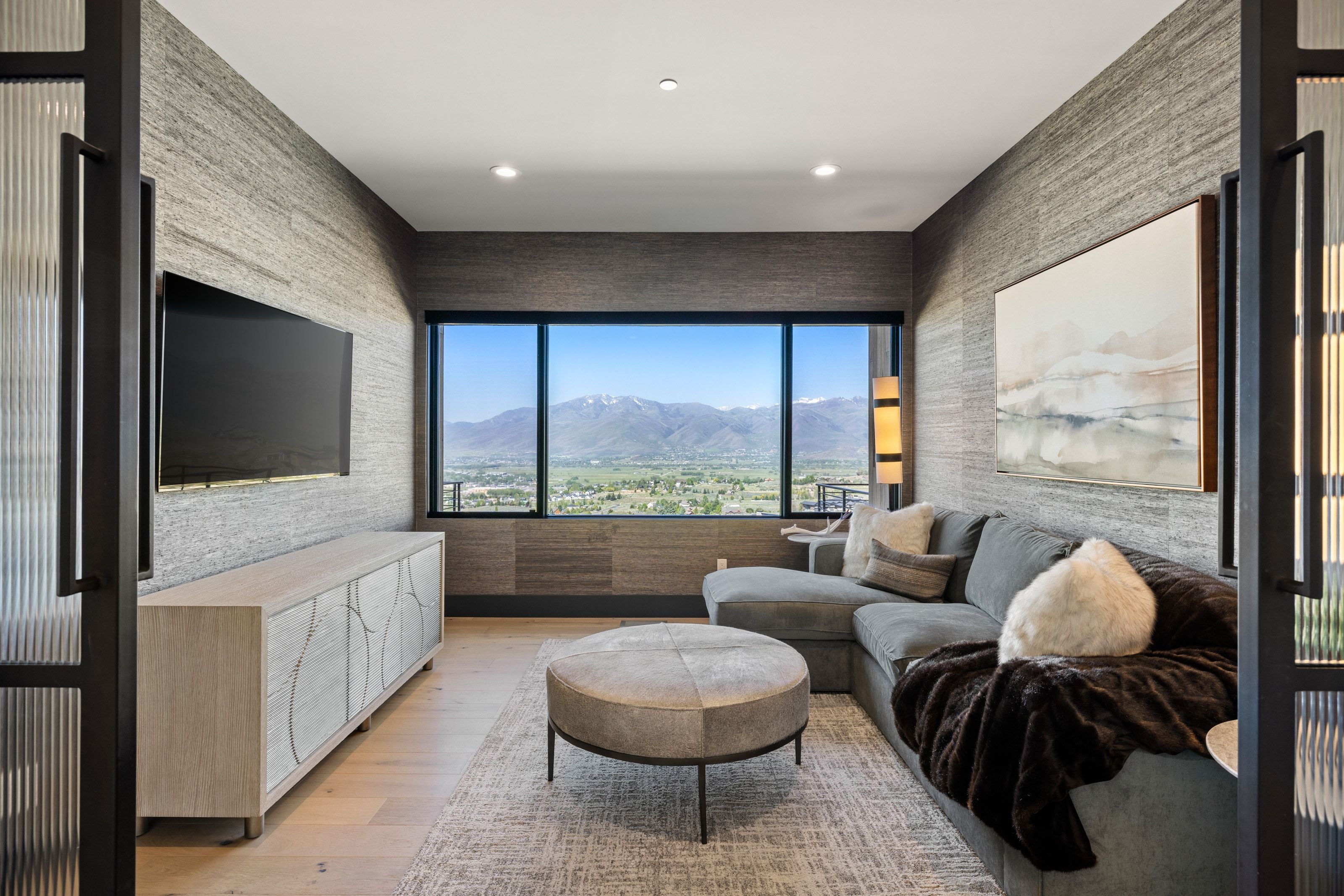 Recessed lighting illuminates wood-finish flooring and textured wall coverings