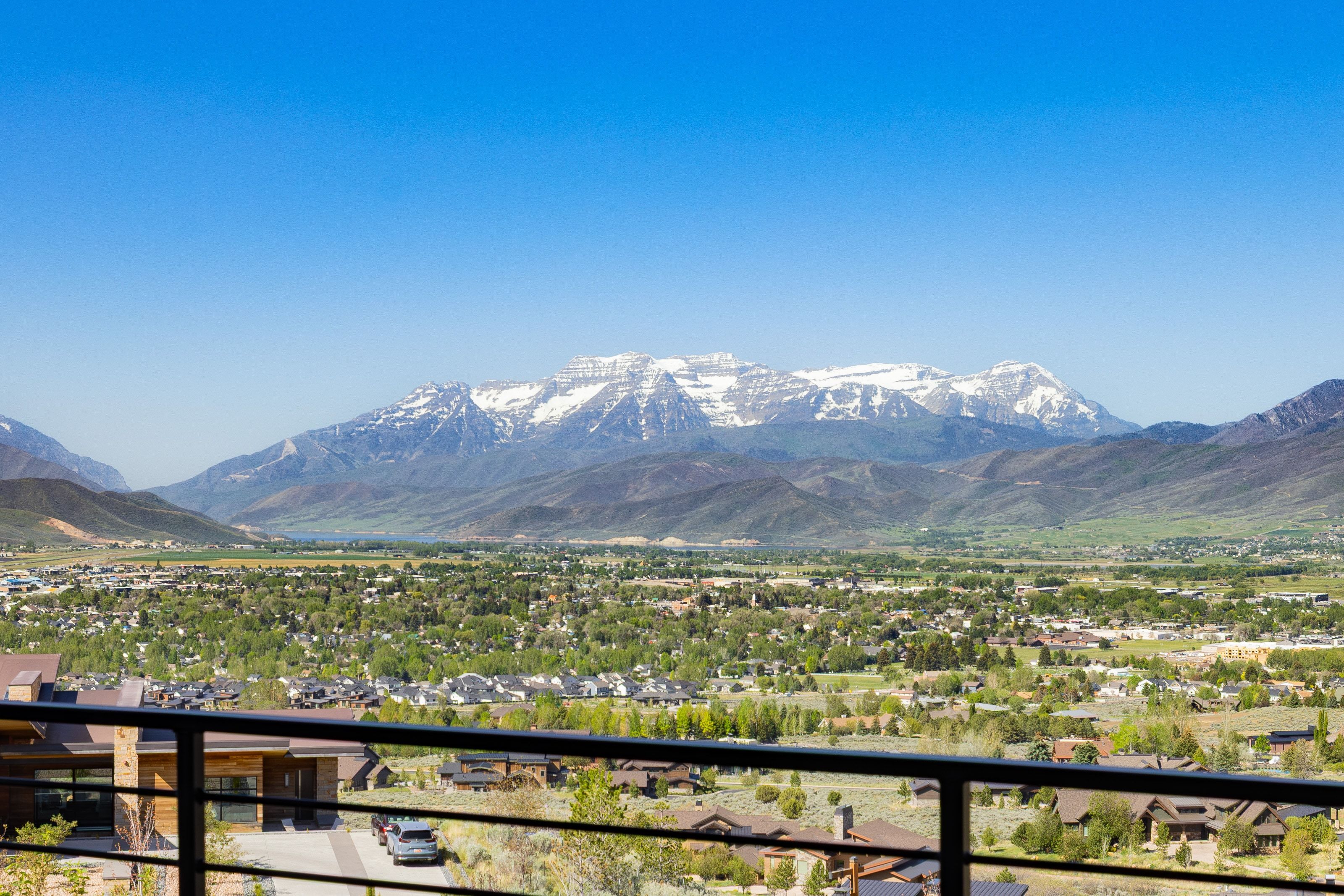 Expansive mountain and valley scenery with a townscape framed by a black metal railing