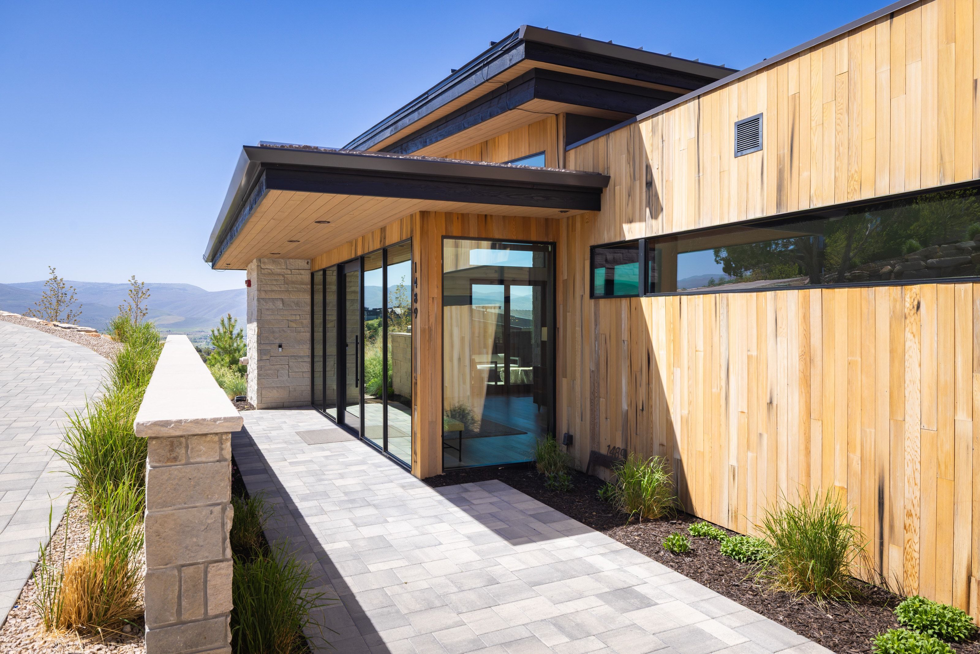 Modern architectural exterior featuring natural wood siding and expansive floor-to-ceiling glass paneling