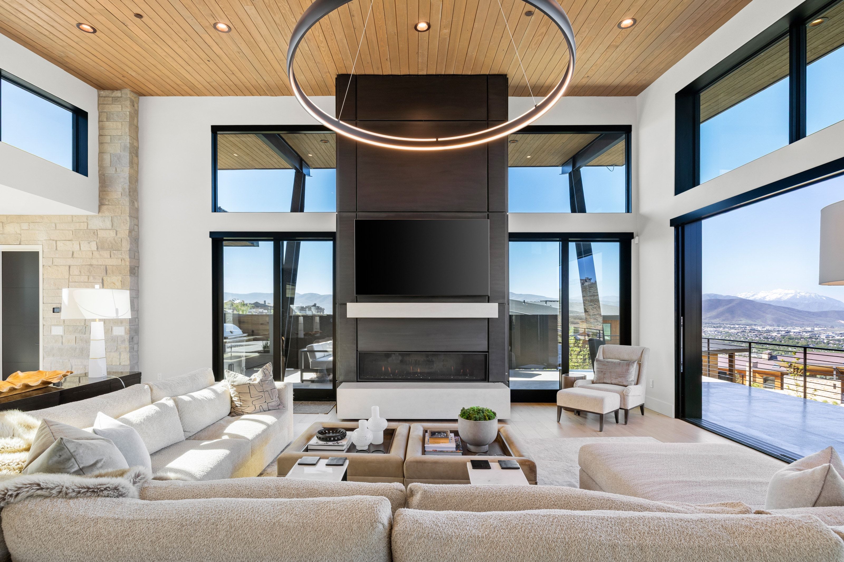 Great room featuring a wood-panel ceiling, stone accent wall, and a built-in media console with a fireplace