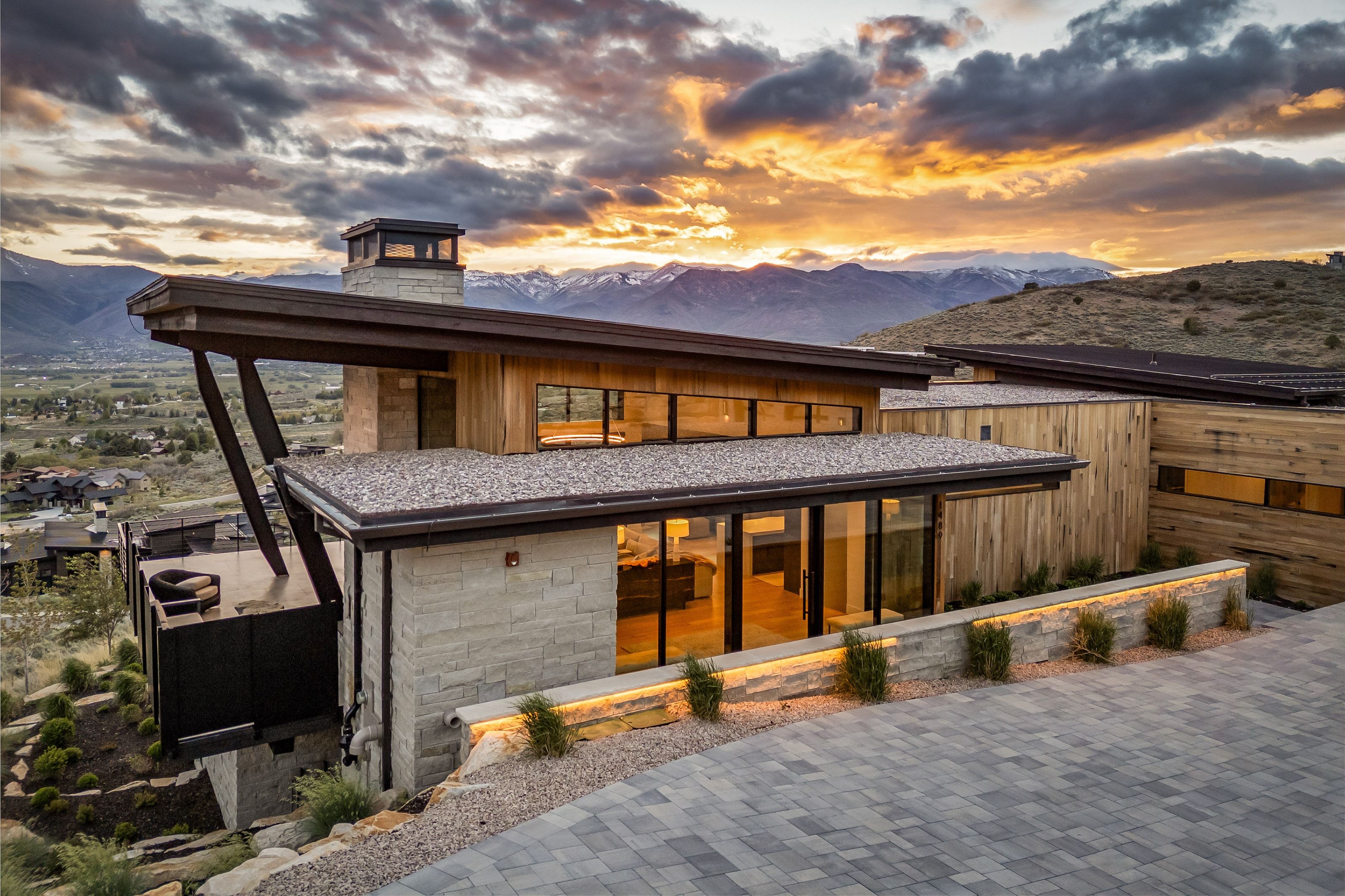 Contemporary architecture featuring stone and wood siding, a flat roof, and expansive window lines