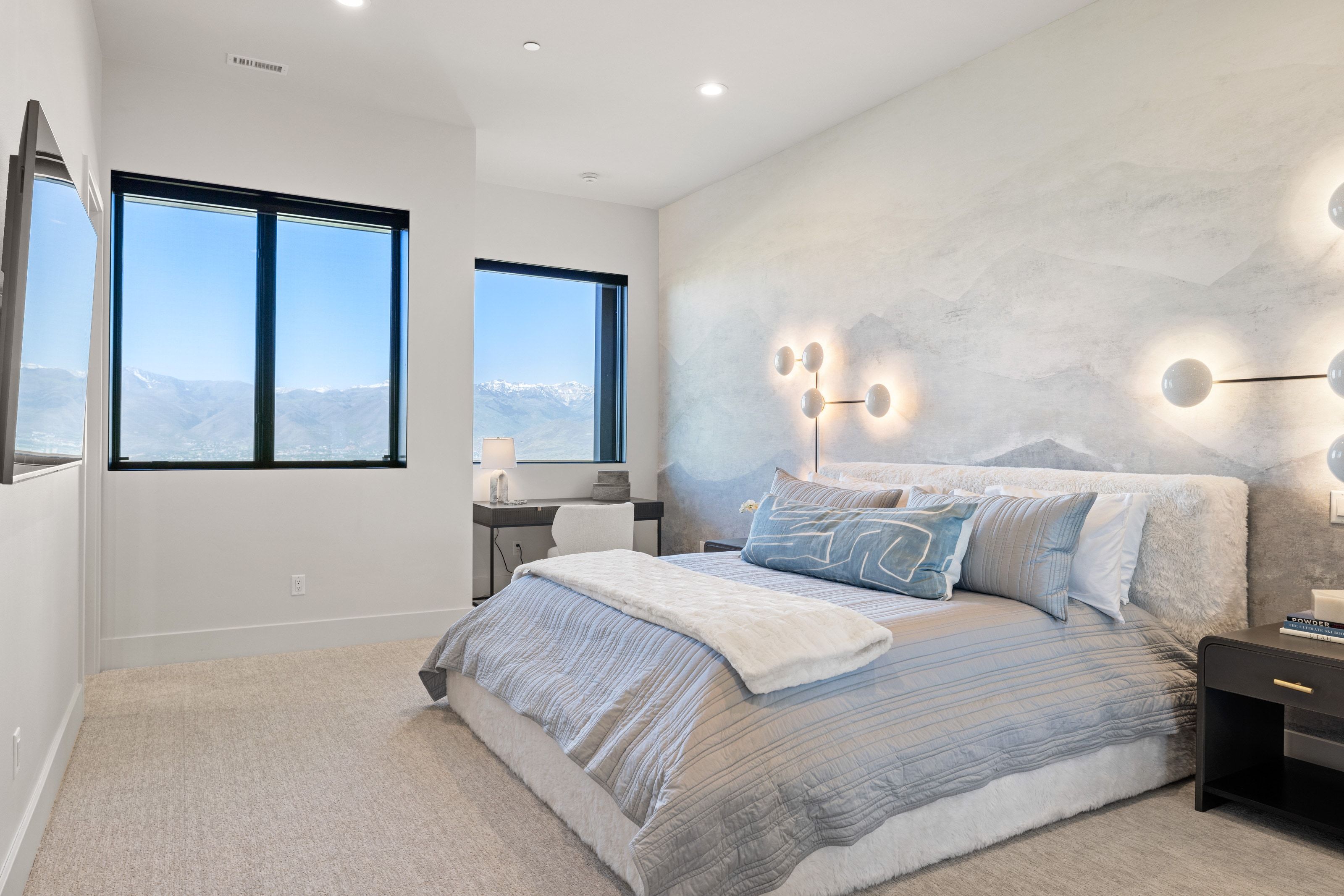 Expansive windows with black trim, recessed lighting, and modern wall sconces