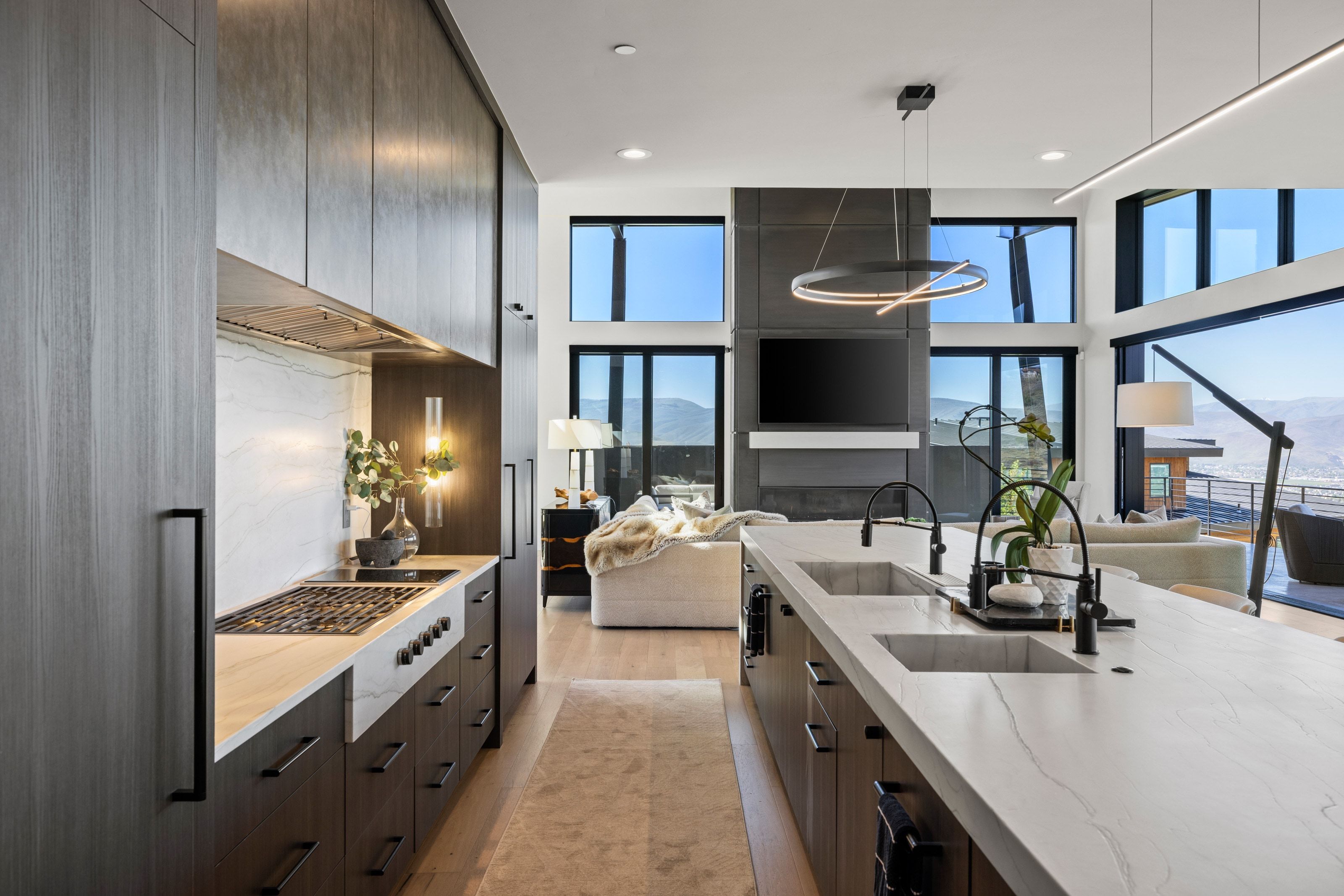 Gourmet kitchen featuring a gas range, large center island with dual sinks, light wood-finish flooring, ample cabinetry, and expansive windows