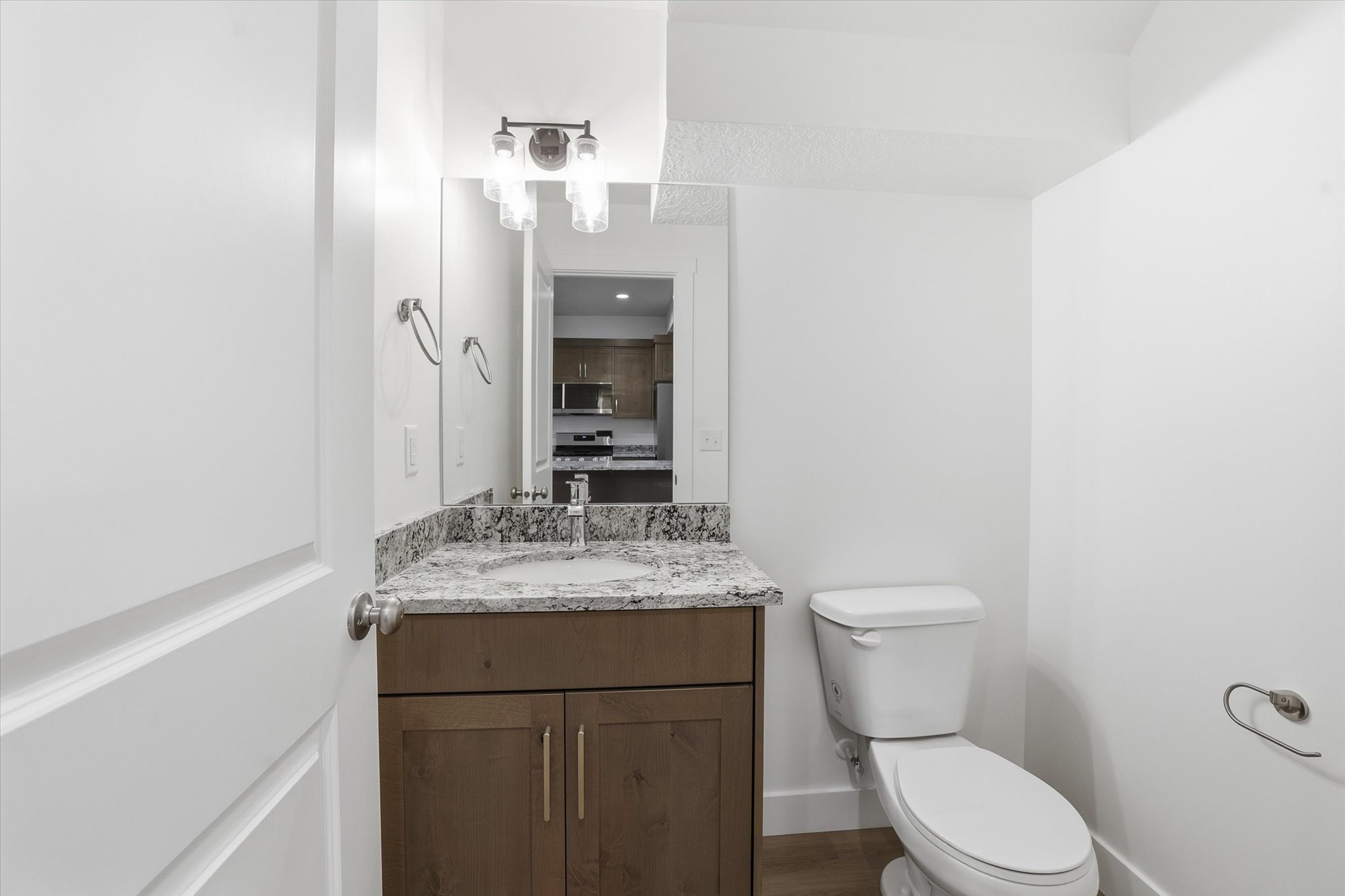 Contemporary bathroom featuring a dark wood-finish vanity with a light speckled countertop and undermount sink