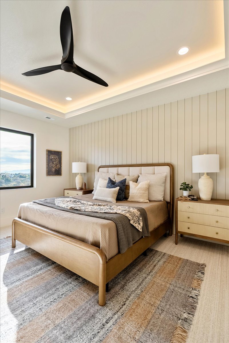 Recessed lighting and cove lighting illuminate a tray ceiling with a modern ceiling fan