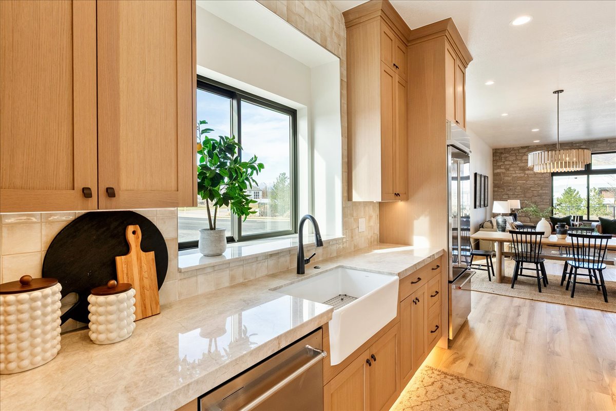 Contemporary kitchen featuring light wood cabinetry, a farmhouse-style sink, and light-toned countertops