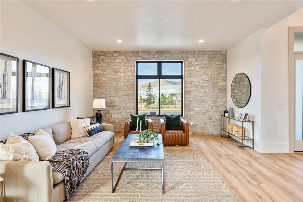Living area featuring a floor-to-ceiling stone accent wall, recessed lighting, wood-finish flooring, and a large black-framed window