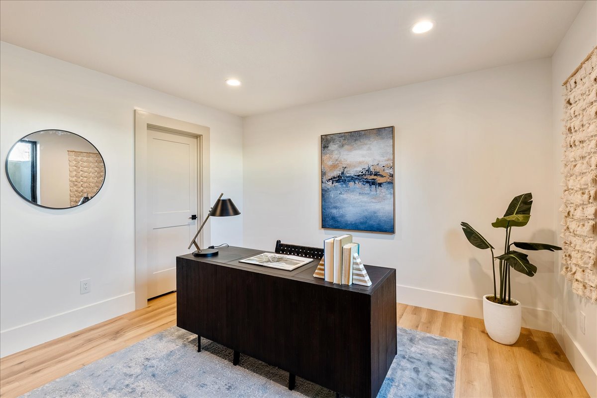 Room featuring light wood-finish flooring, recessed ceiling lighting, a contemporary door with dark hardware, and a partial exposed brick wall