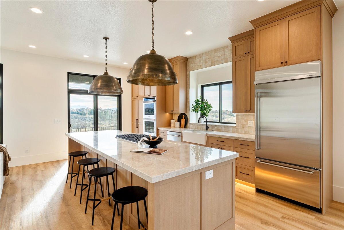 Spacious kitchen featuring a large island with stone countertops, built-in cooktop, and seating